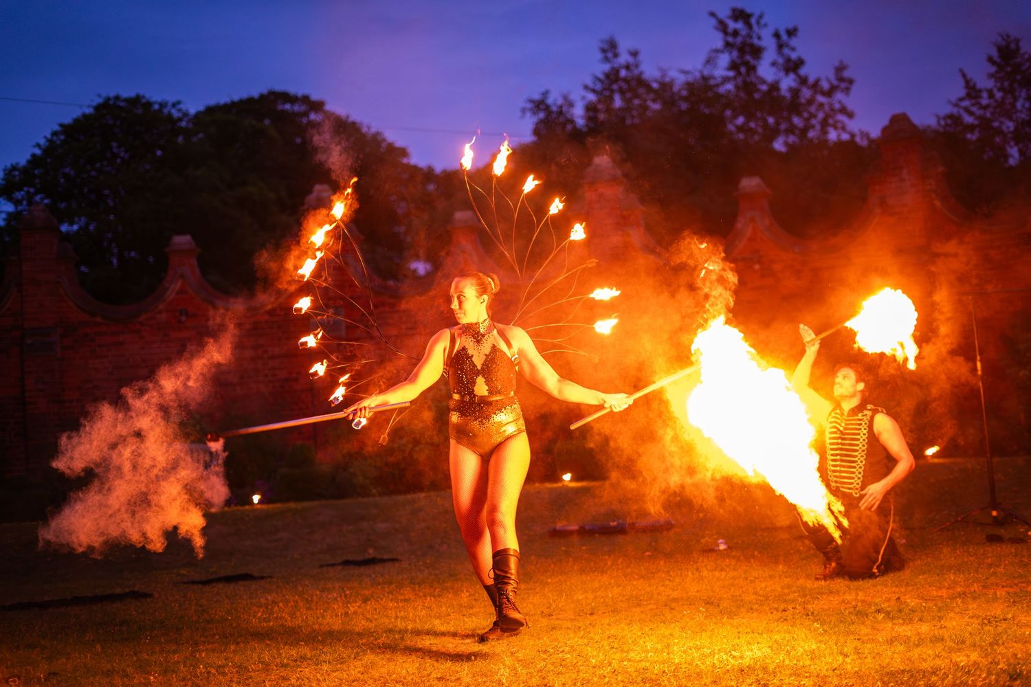 Fire dancers creating spectacular flame trails against a purple twilight sky.