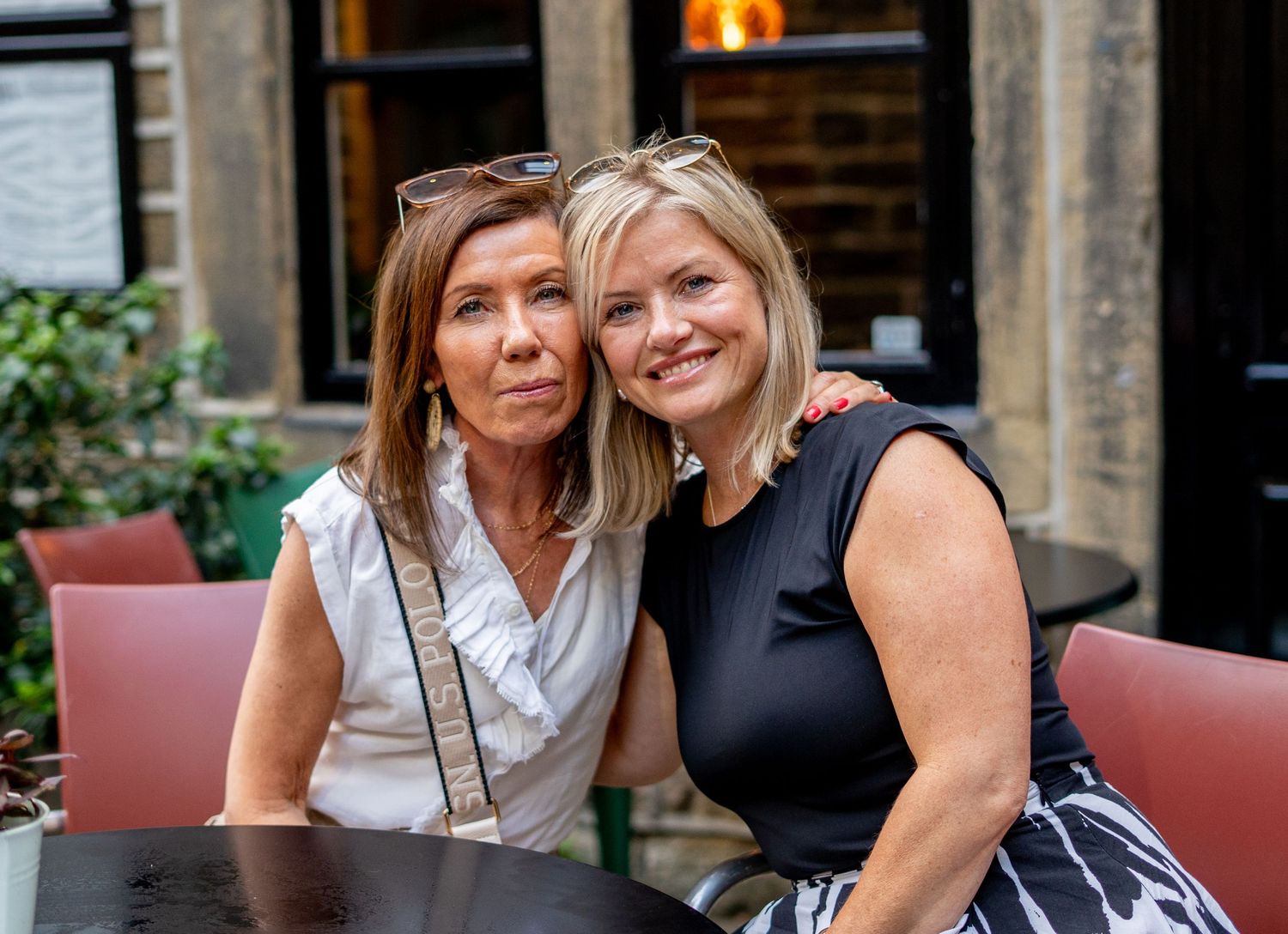Friends enjoying drinks on an outdoor patio with modern furnishings.