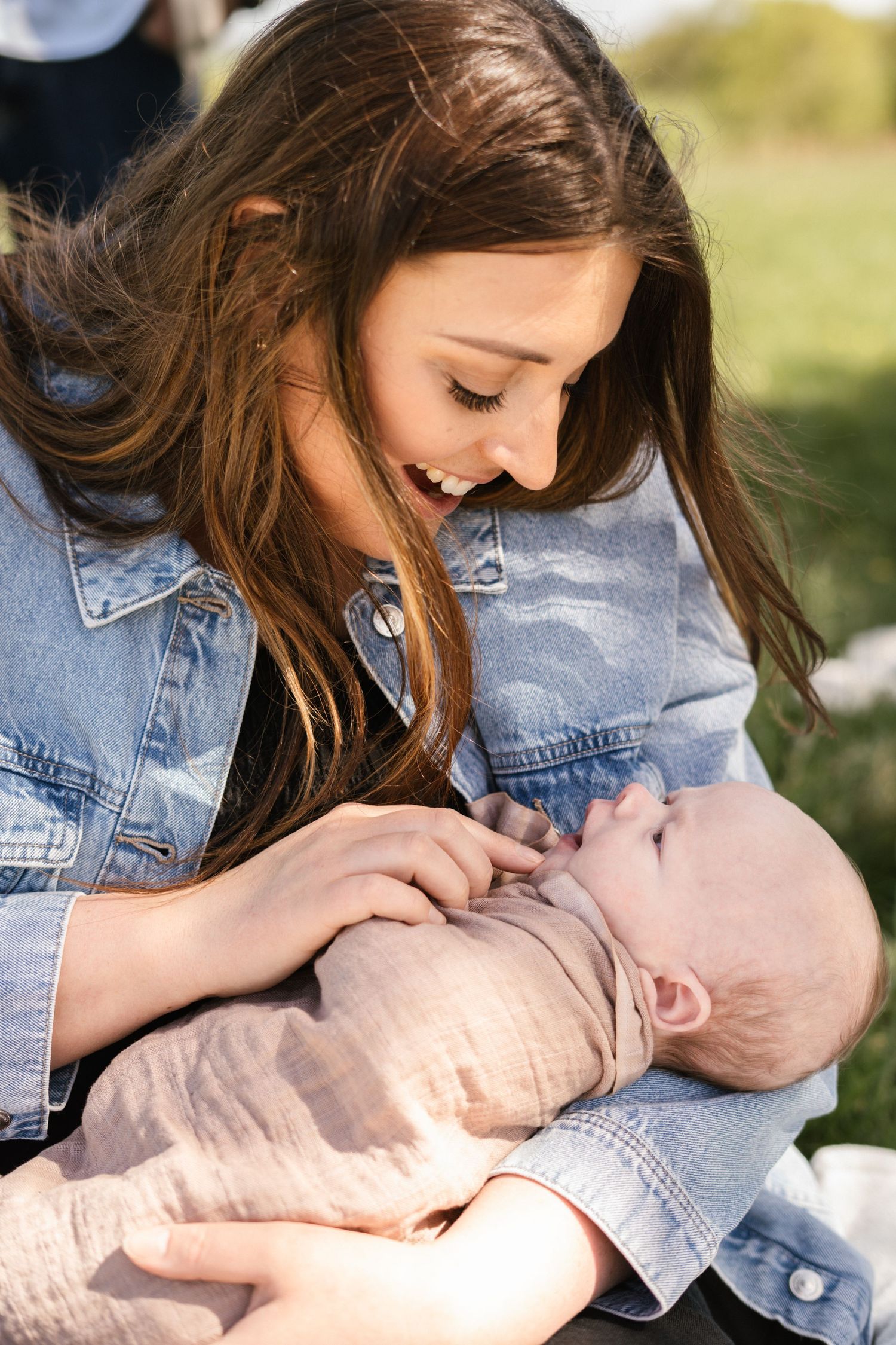 Gentle moments between parent and baby wearing denim jacket outdoors.