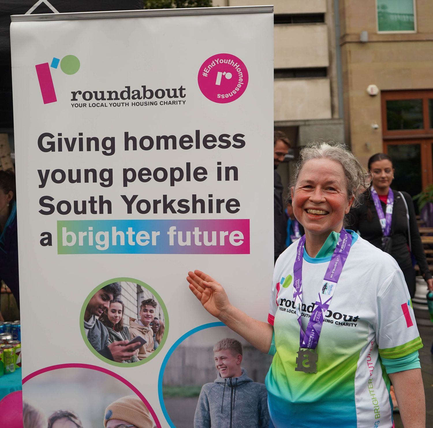 Participant poses with Roundabout charity banner supporting homeless youth in South Yorkshire.