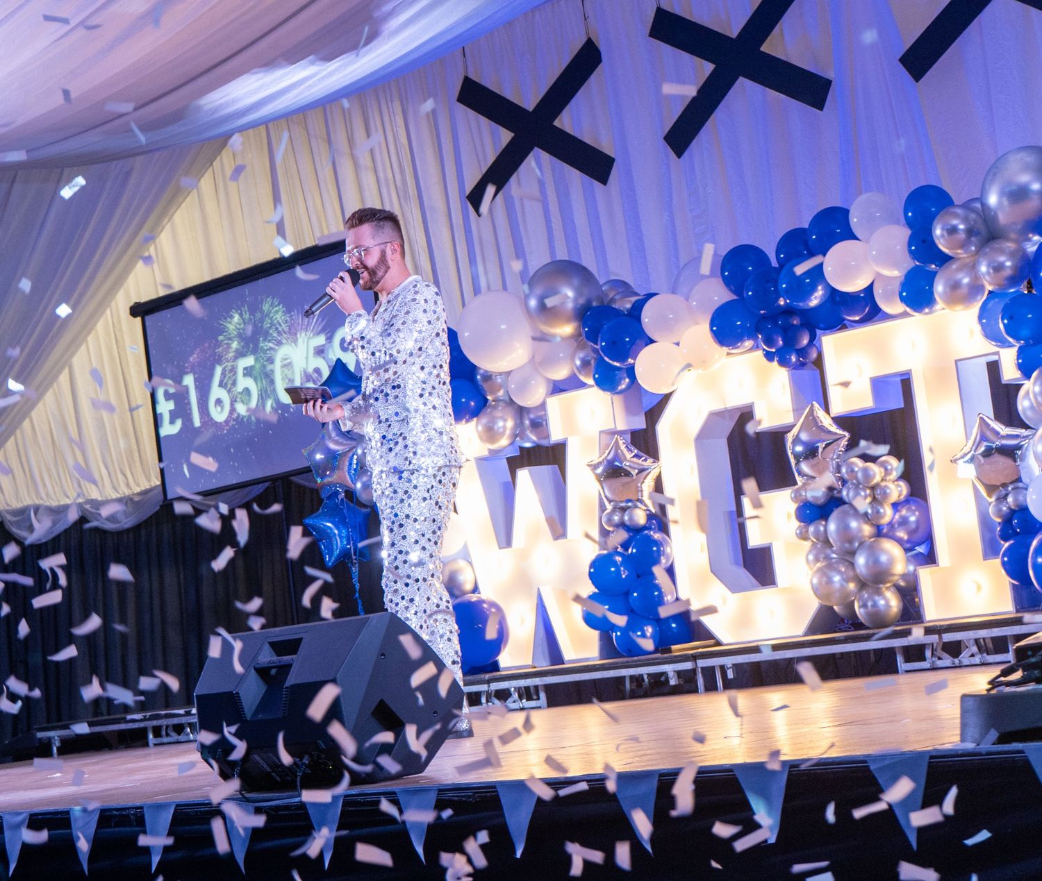 Event celebration with WCT sign, blue balloons, and confetti against white backdrop.
