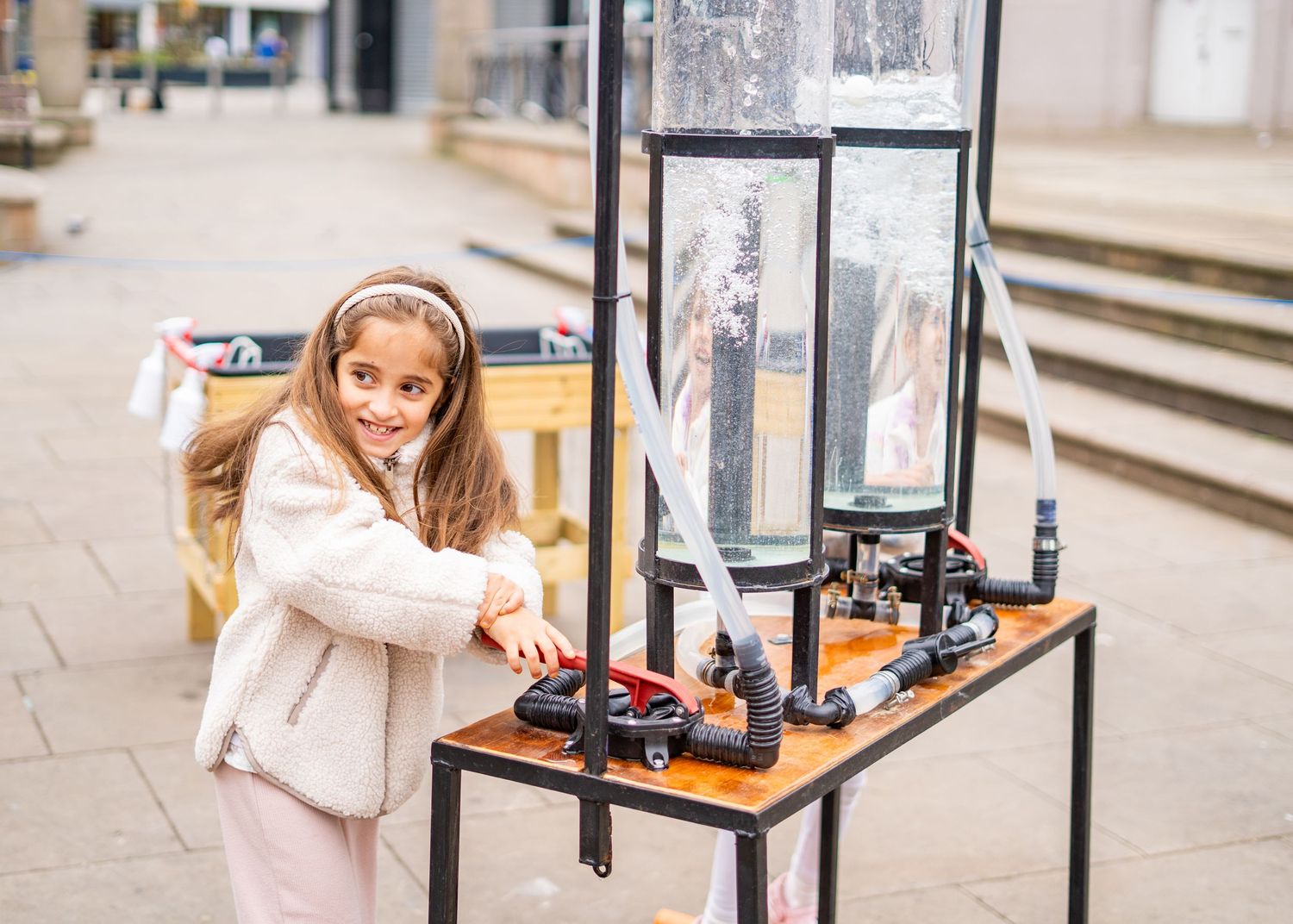 Close-up view of an interactive science experiment station with black metal frame and clear display.