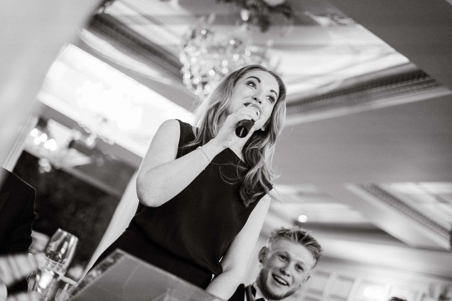 Black and white photograph of guests mingling at a formal indoor celebration.