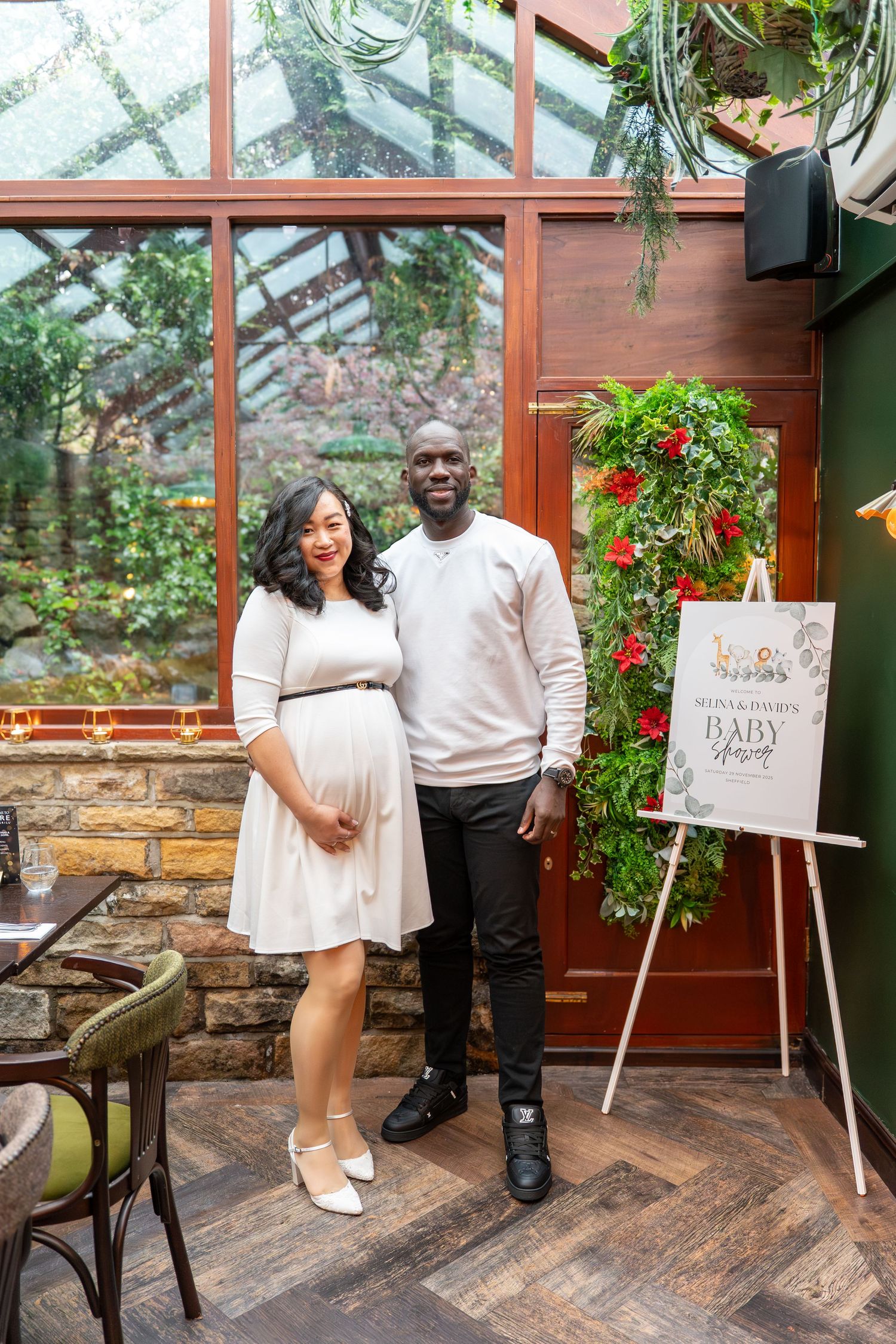 Baby shower celebration in a greenhouse-style venue with wooden floors and stone walls.