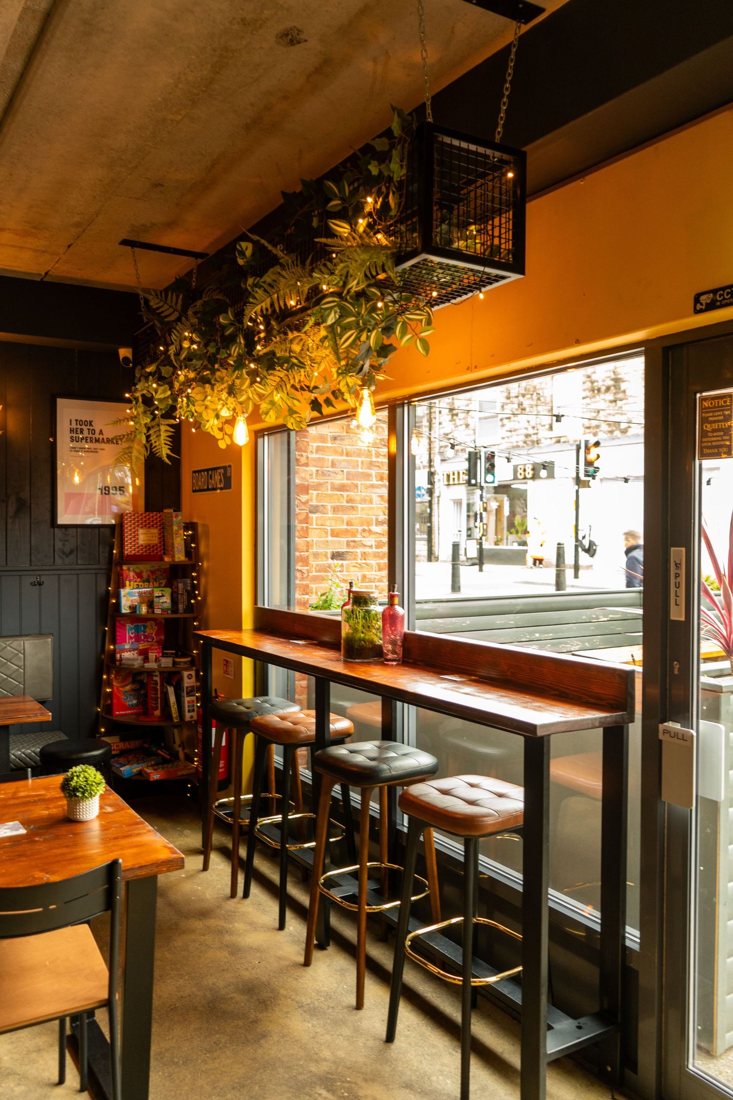 Modern bar interior with wooden tables, bar stools and large windows providing natural light.