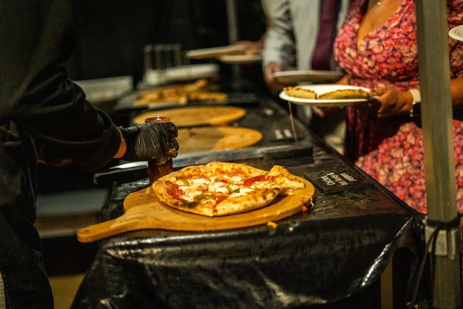 Fresh pizzas being prepared and served on wooden cutting boards.