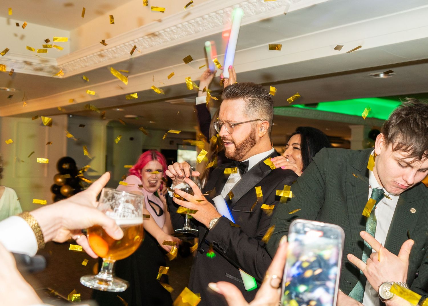 Gold confetti raining down on party guests in a bright indoor venue.