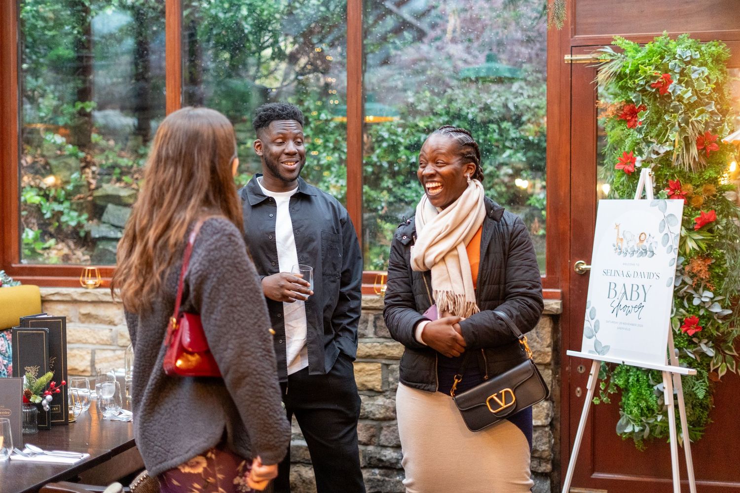 Social gathering in a rustic venue with wooden panels and decorative greenery.
