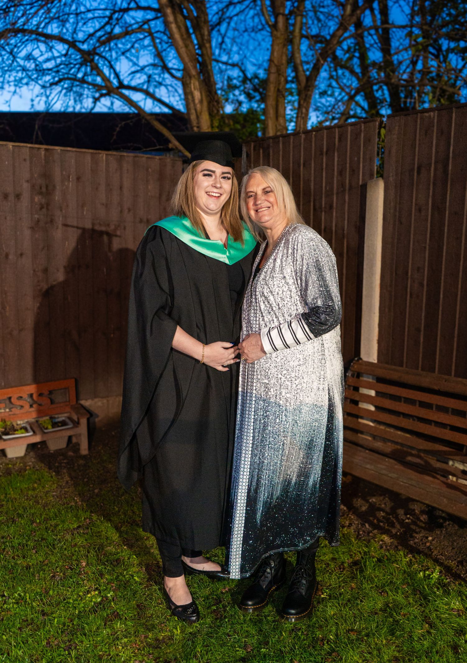 A graduation portrait session featuring celebratory poses against a wooden fence.