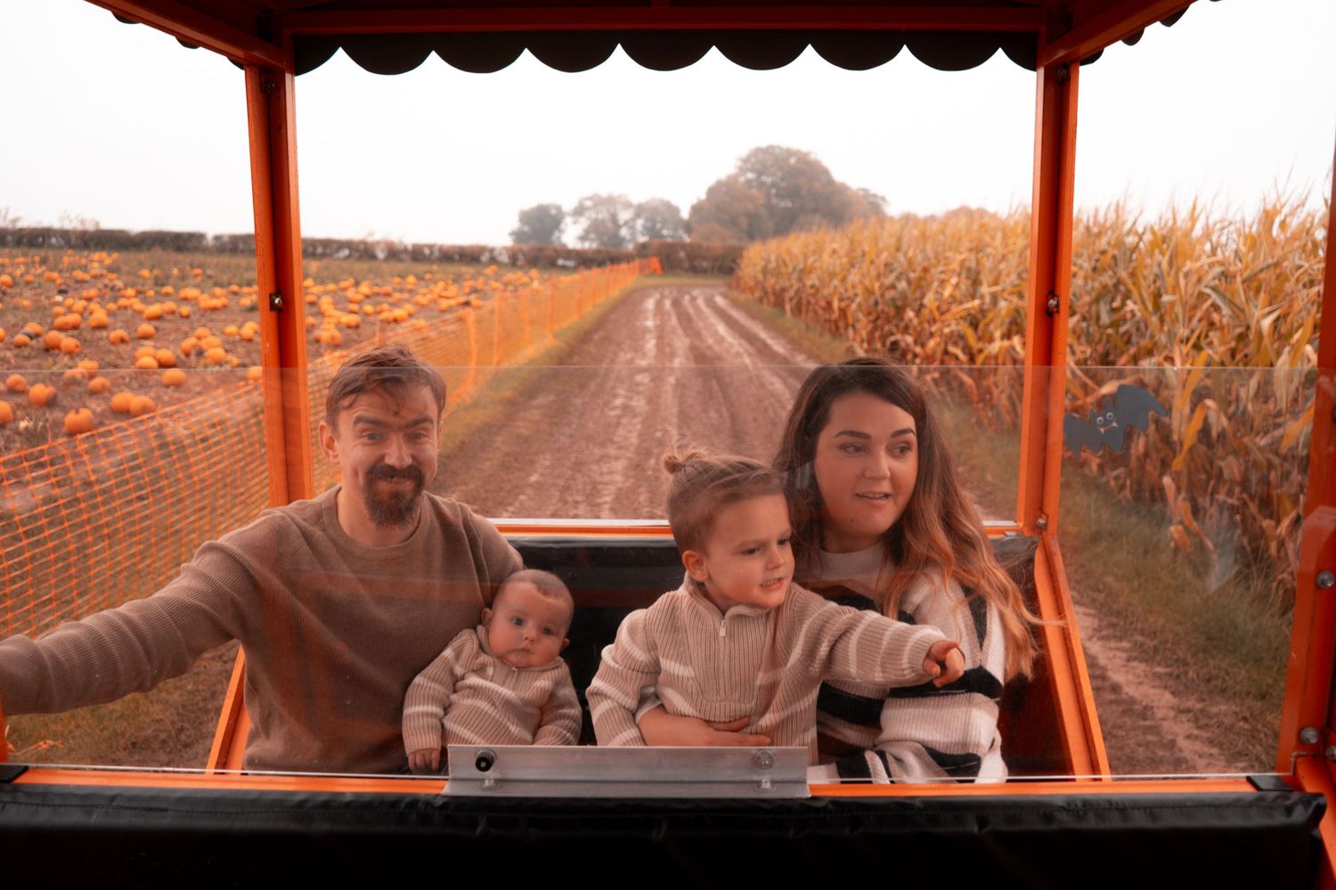 Family enjoying a hayride through autumn fields at sunset.