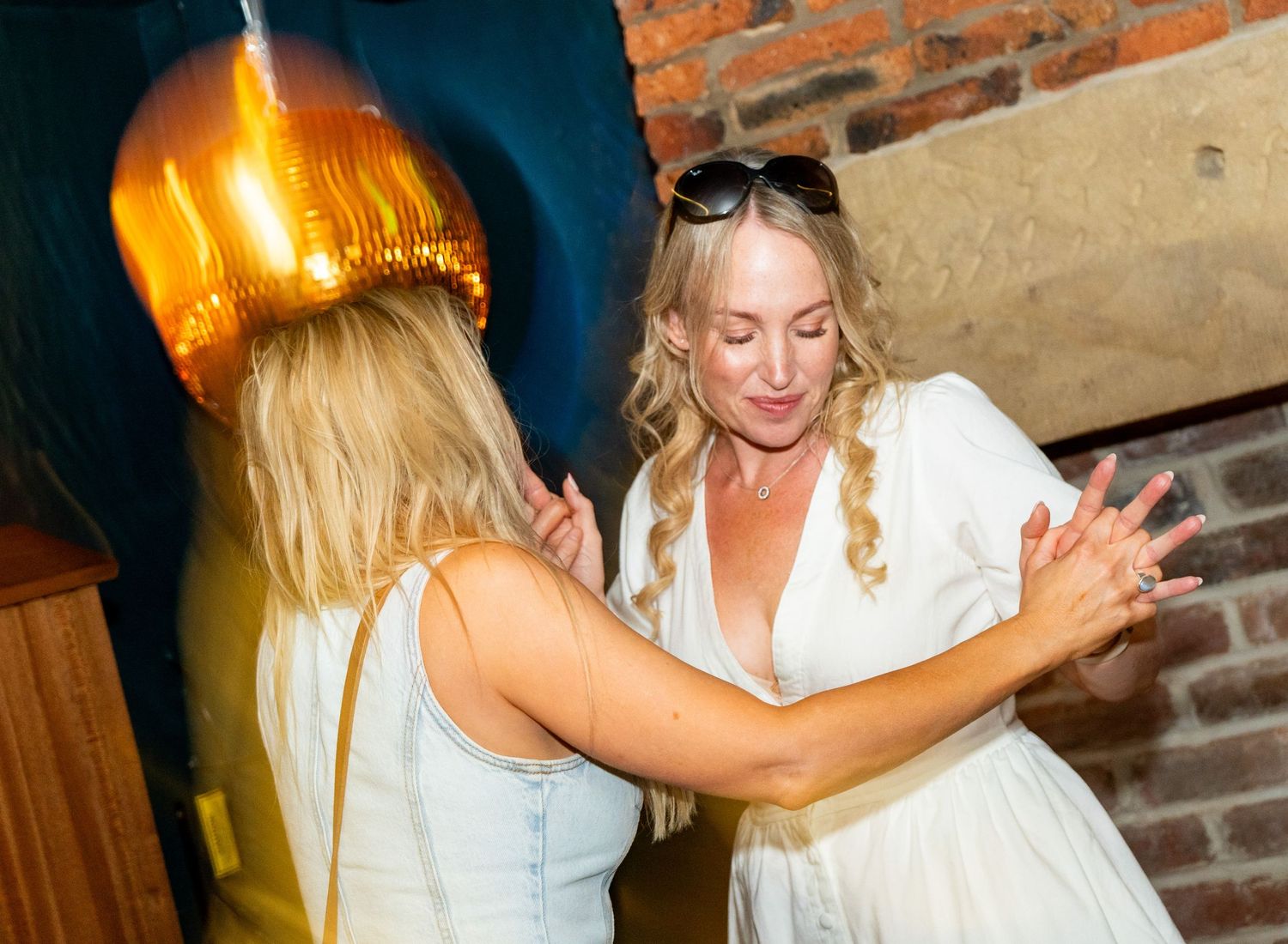 People dancing and celebrating in a dimly lit venue with brick walls.