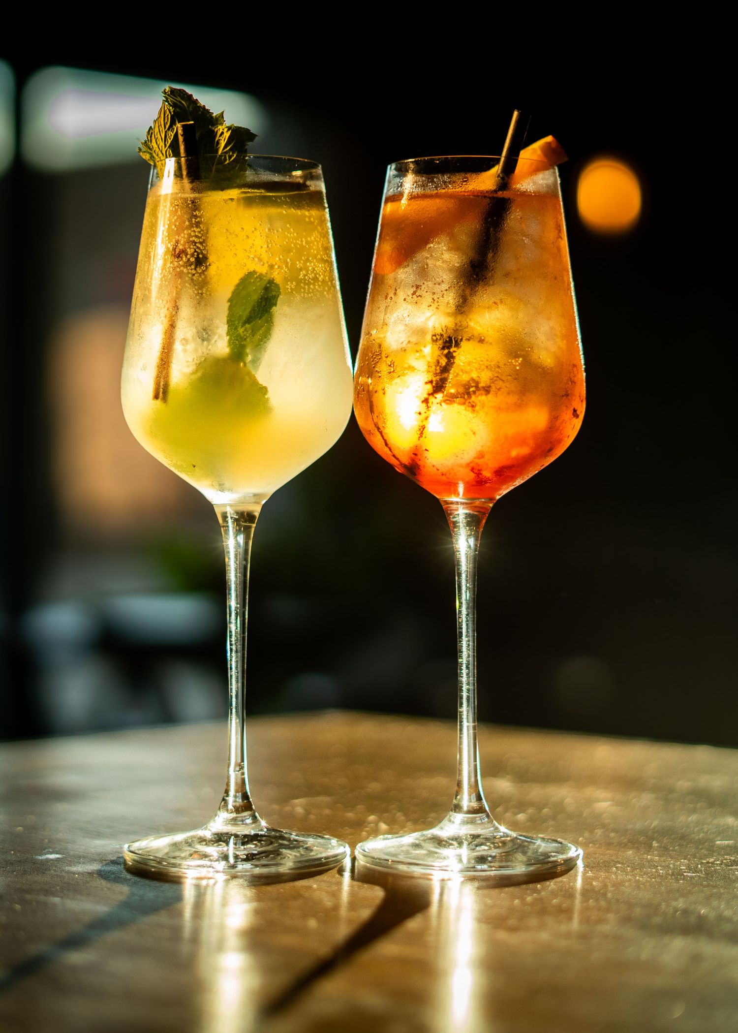 Three elegant cocktails with citrus and herb garnishes on textured surface.
