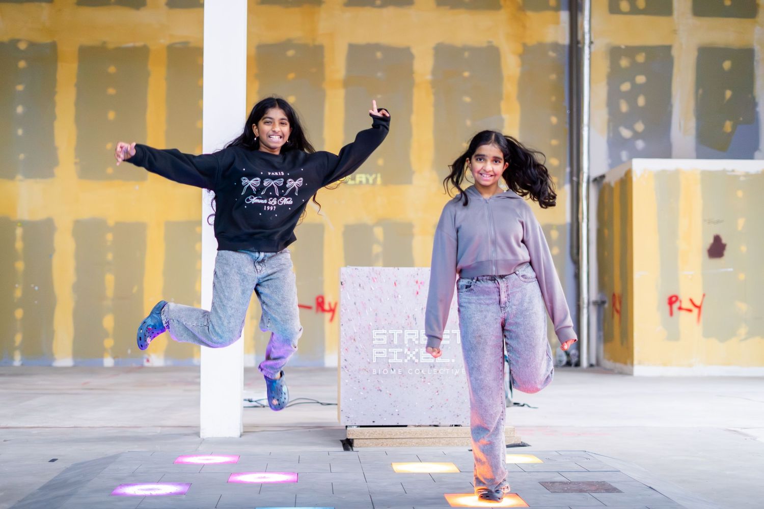Children playing and jumping in a brightly lit indoor space with yellow walls.