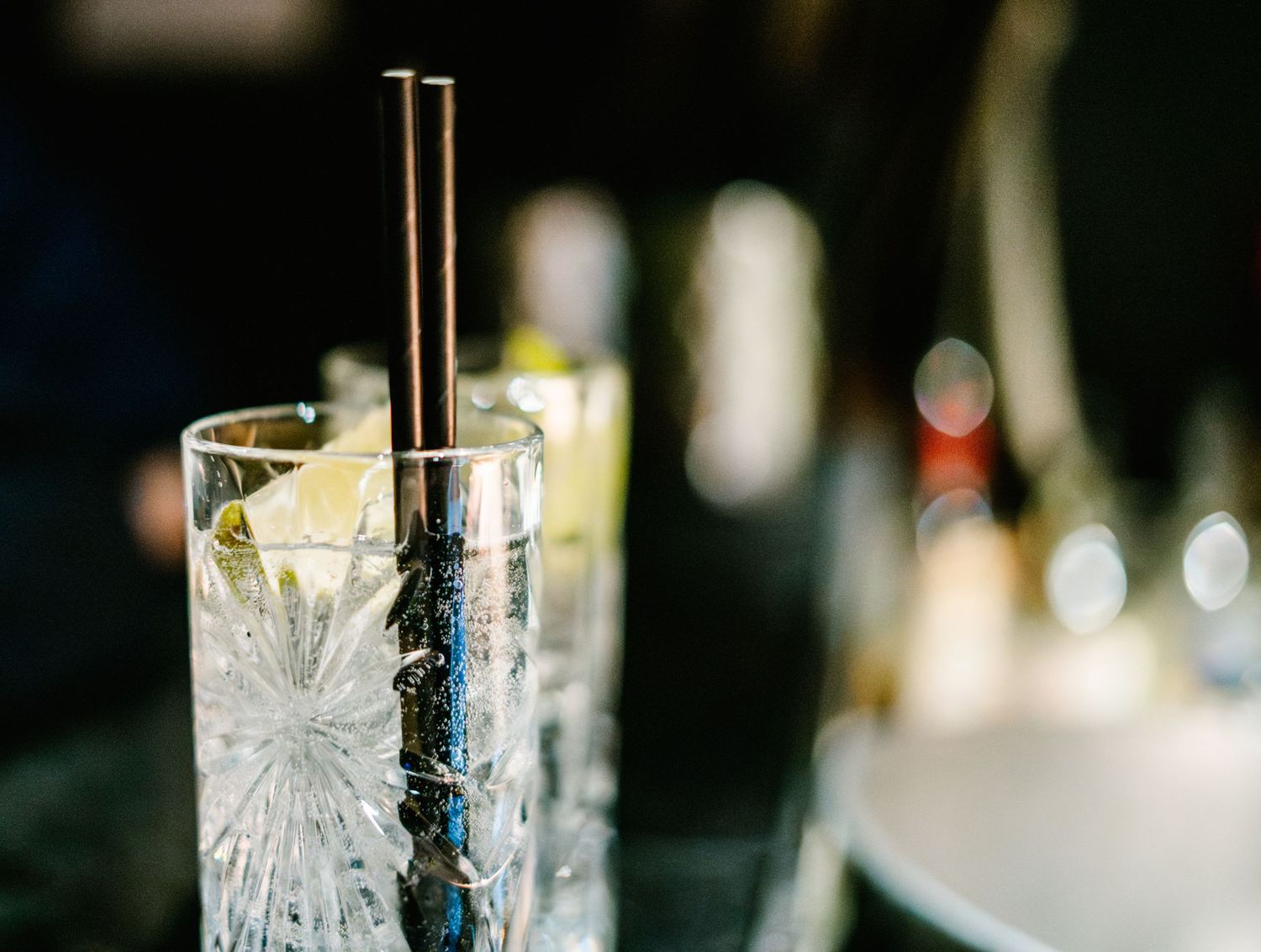 Liquid being poured into an ornate crystal cocktail glass on a textured bar surface.
