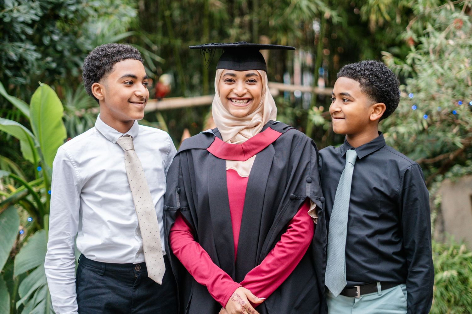 Family graduation portrait taken in lush garden setting with greenery.