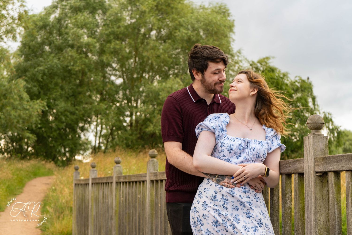 Romantic photoshoot on wooden walkway with scenic lake views.