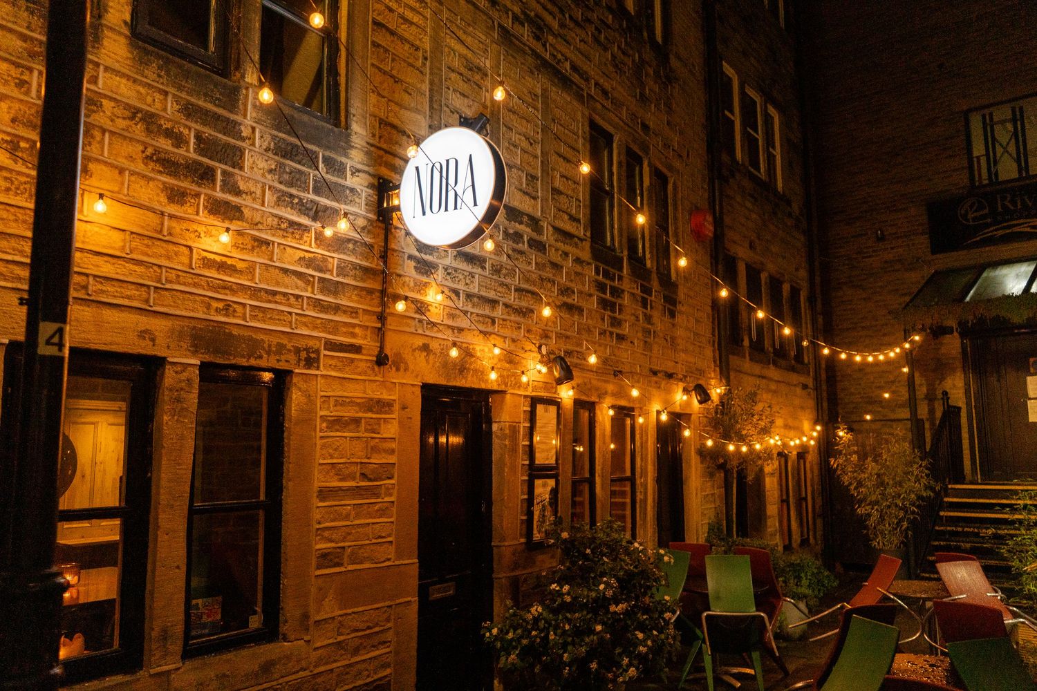 Historic brick building exterior with string lights and vintage lanterns creating an inviting evening ambiance.