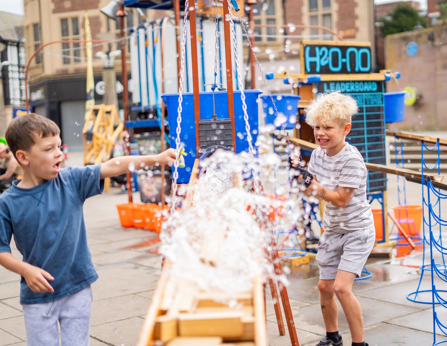 Children playing with water splash exhibits at an outdoor science museum.