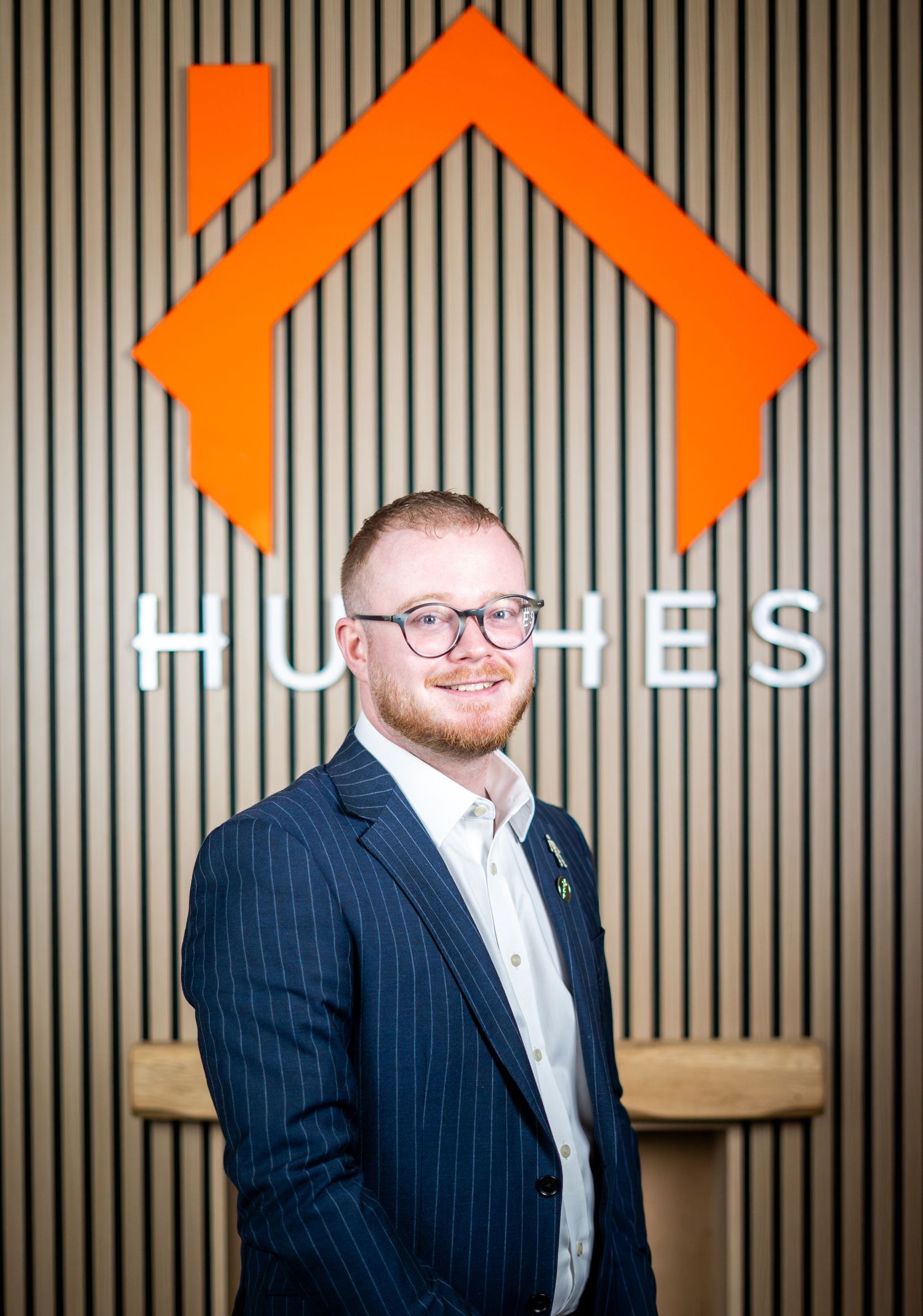 Business portrait against wooden wall with orange geometric patterns.