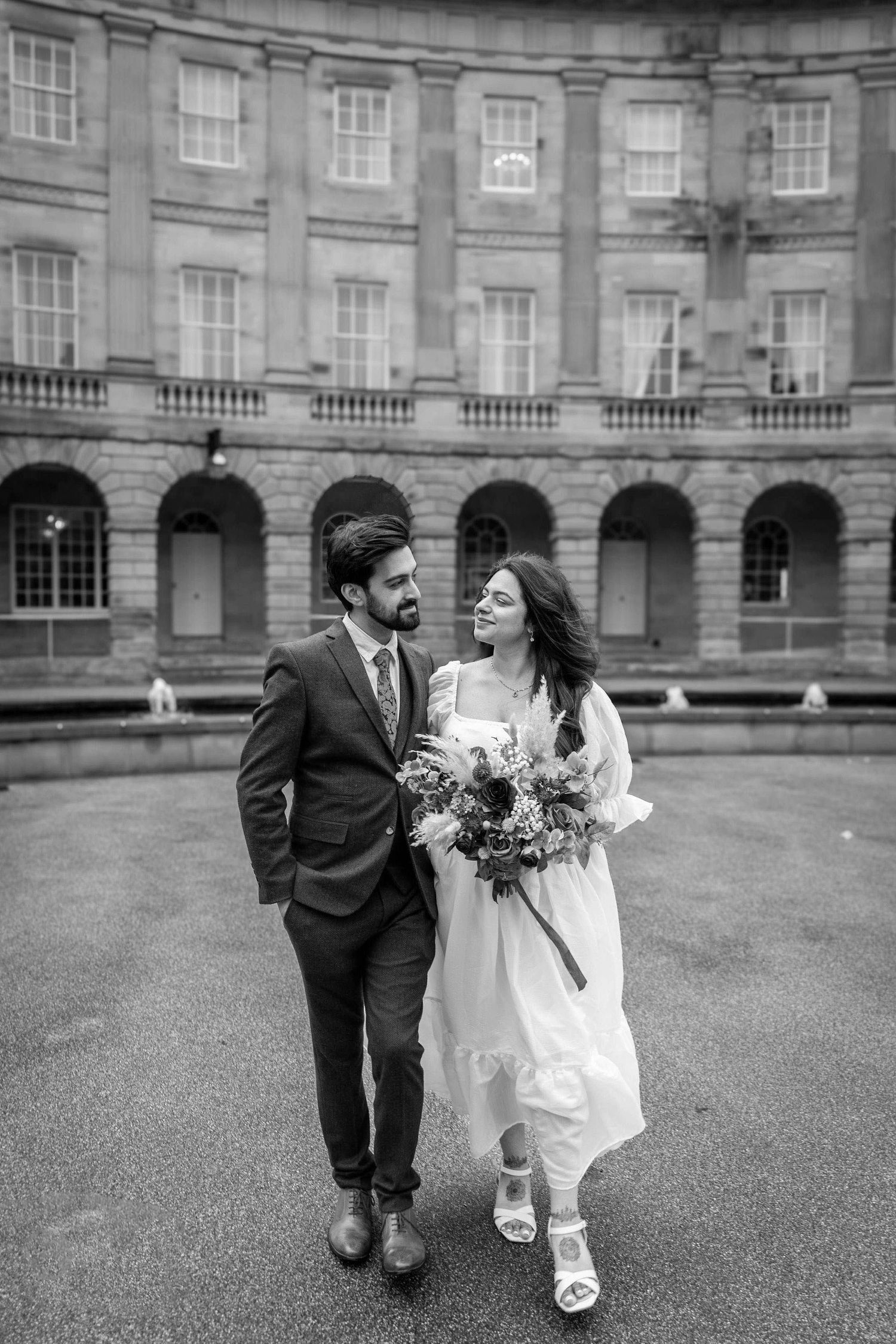 Black and white wedding photos taken in front of a grand historic building with stone columns.