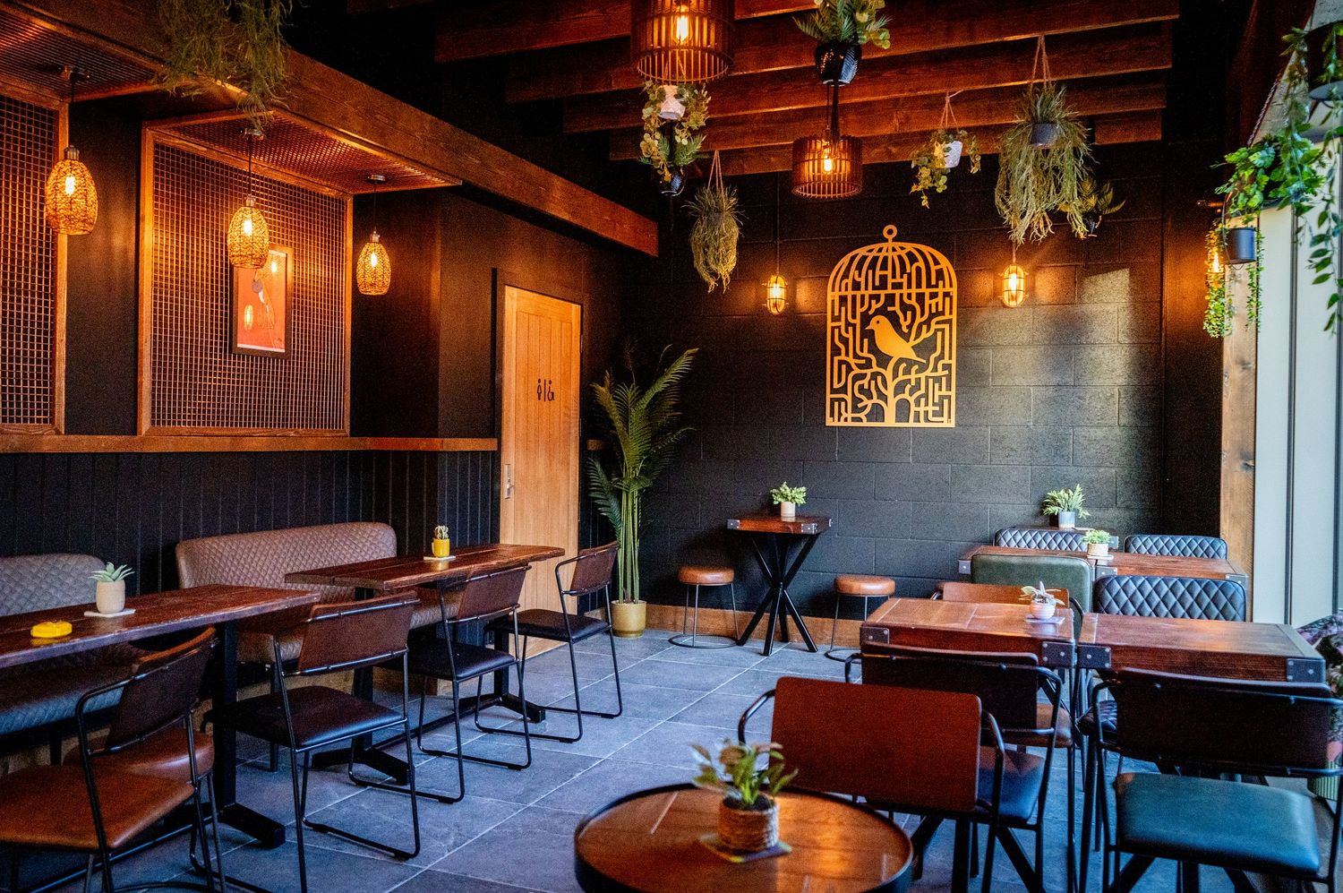 Cozy restaurant interior with wooden tables, hanging lights, and decorative wall features.