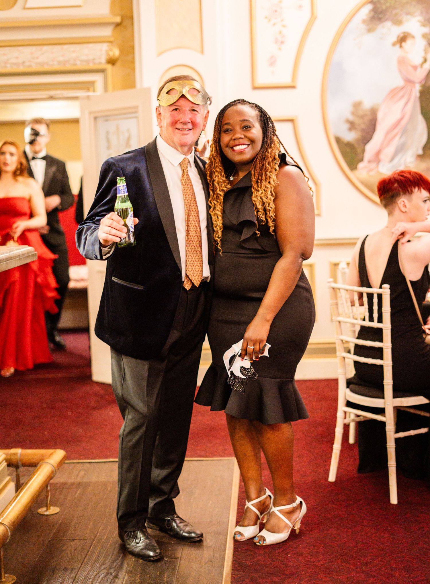 Guests in formal attire enjoying evening celebration in ornate ballroom setting.