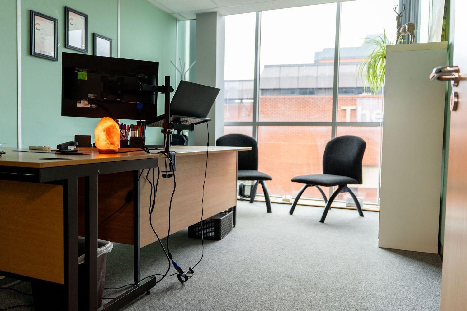Professional office interior with desk setup and seating area near large windows.