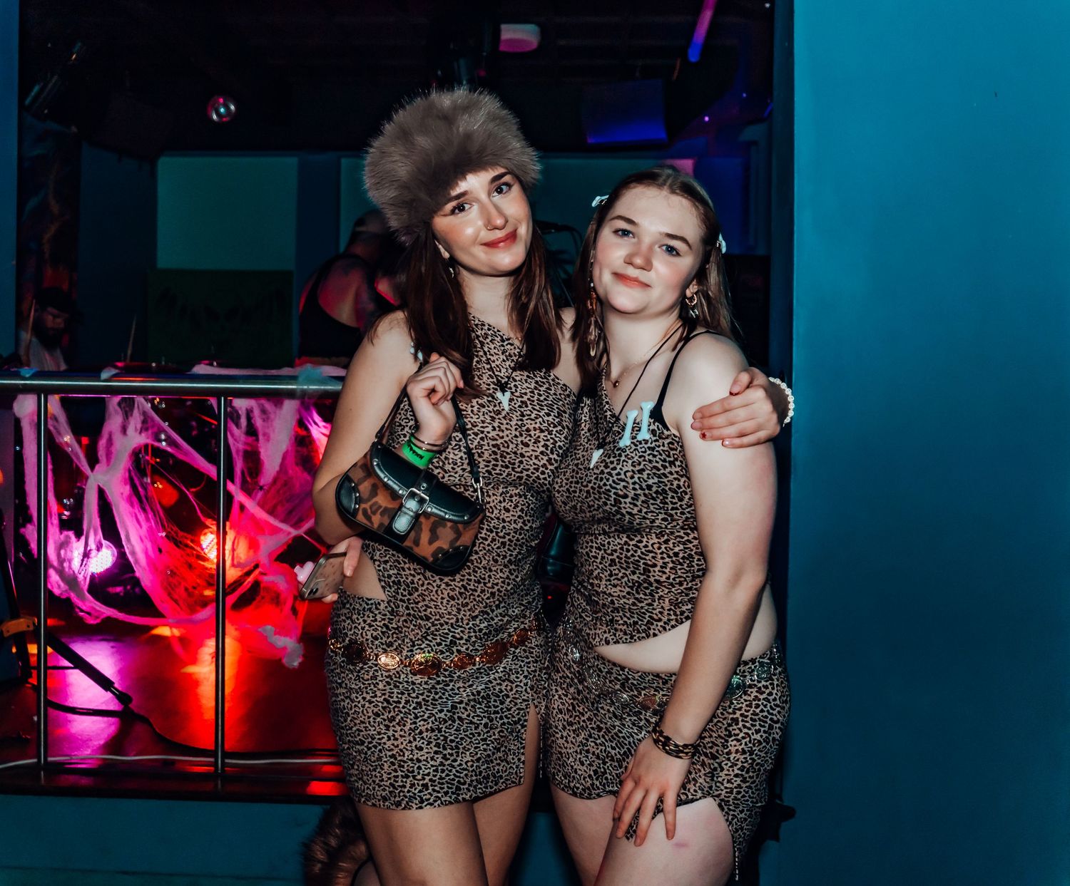 Club scene with partygoers in leopard print outfits under purple lighting.