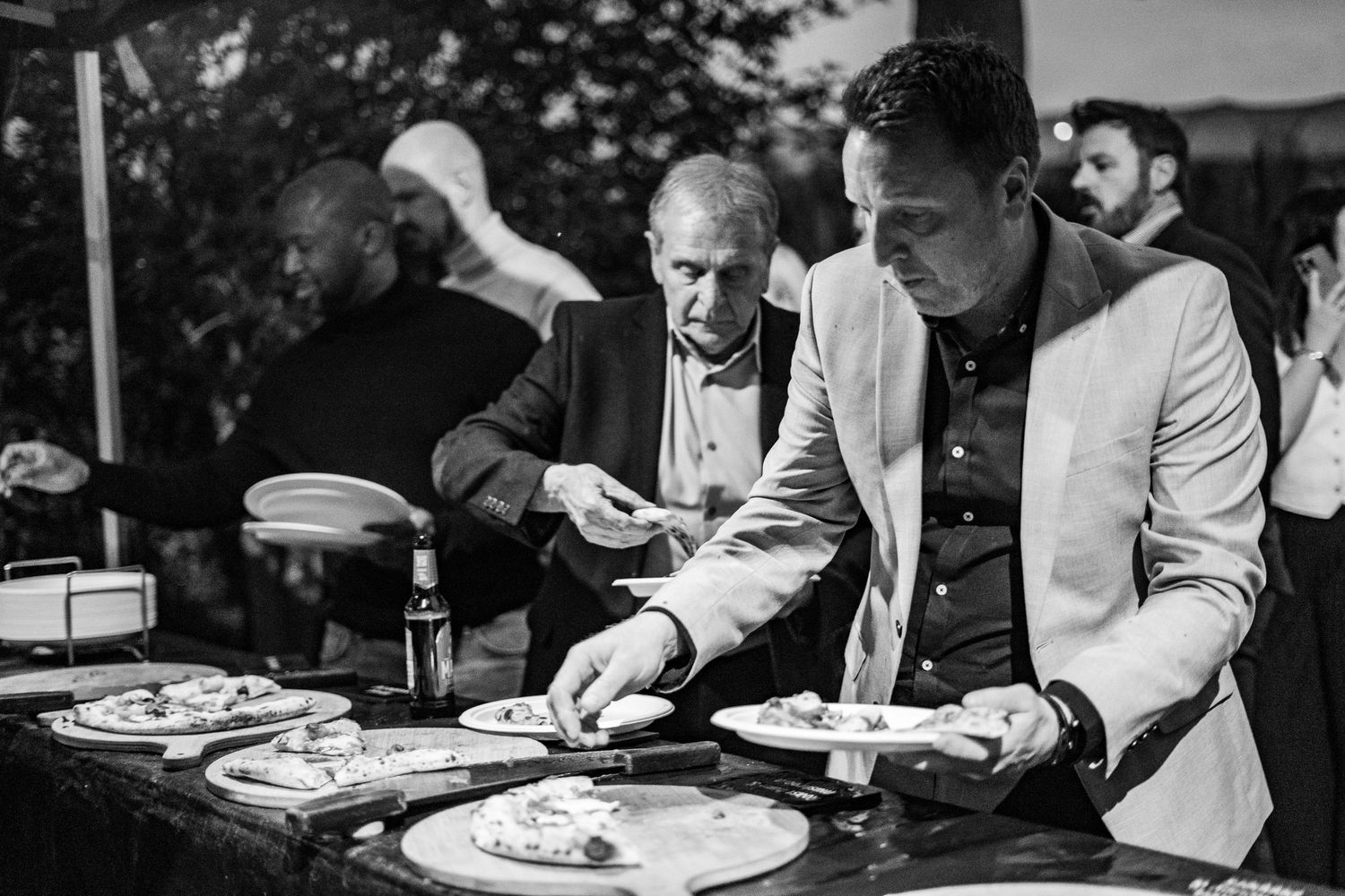 Professional chefs preparing pizzas at an outdoor catering event.