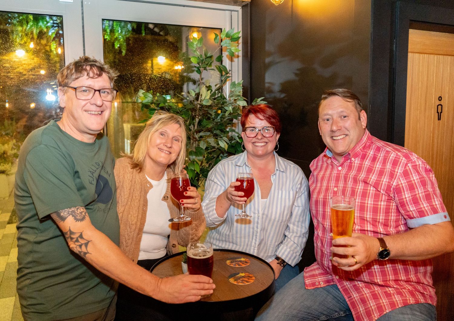 Friends gathering at a pub table enjoying drinks and conversation under warm lighting.