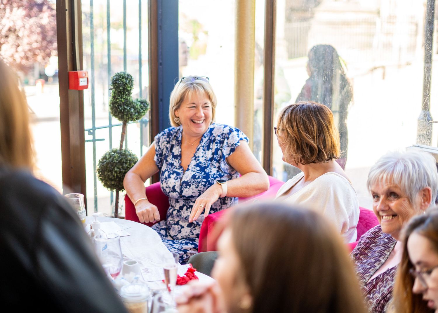 Guests gathered at tables during a baby shower celebration with natural lighting.