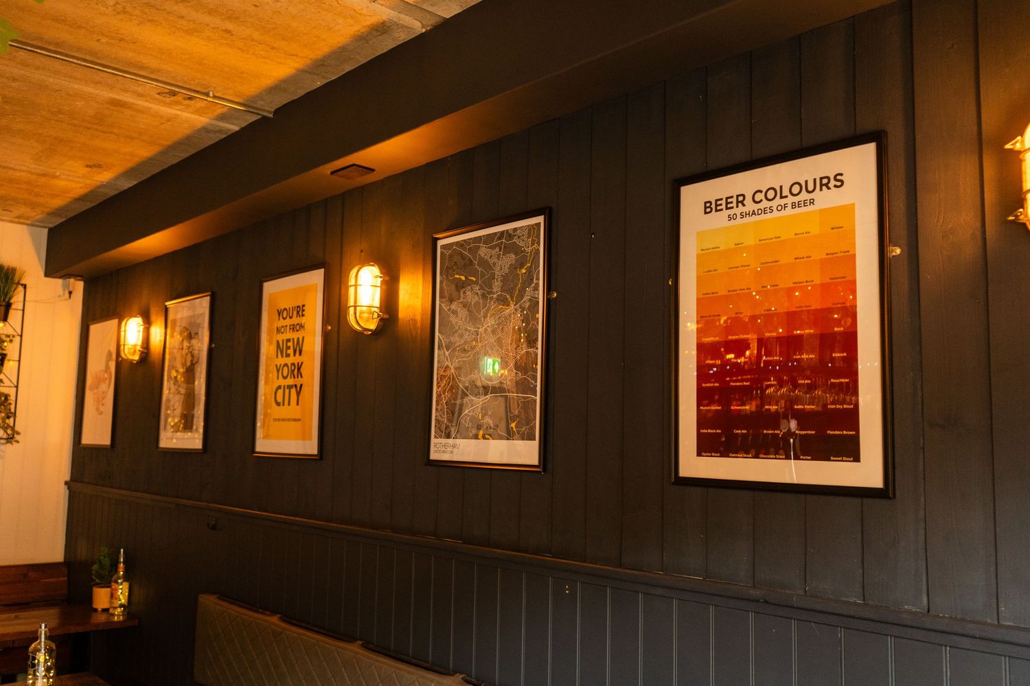 Bar interior with wood paneled walls decorated with framed artwork and warm lighting.
