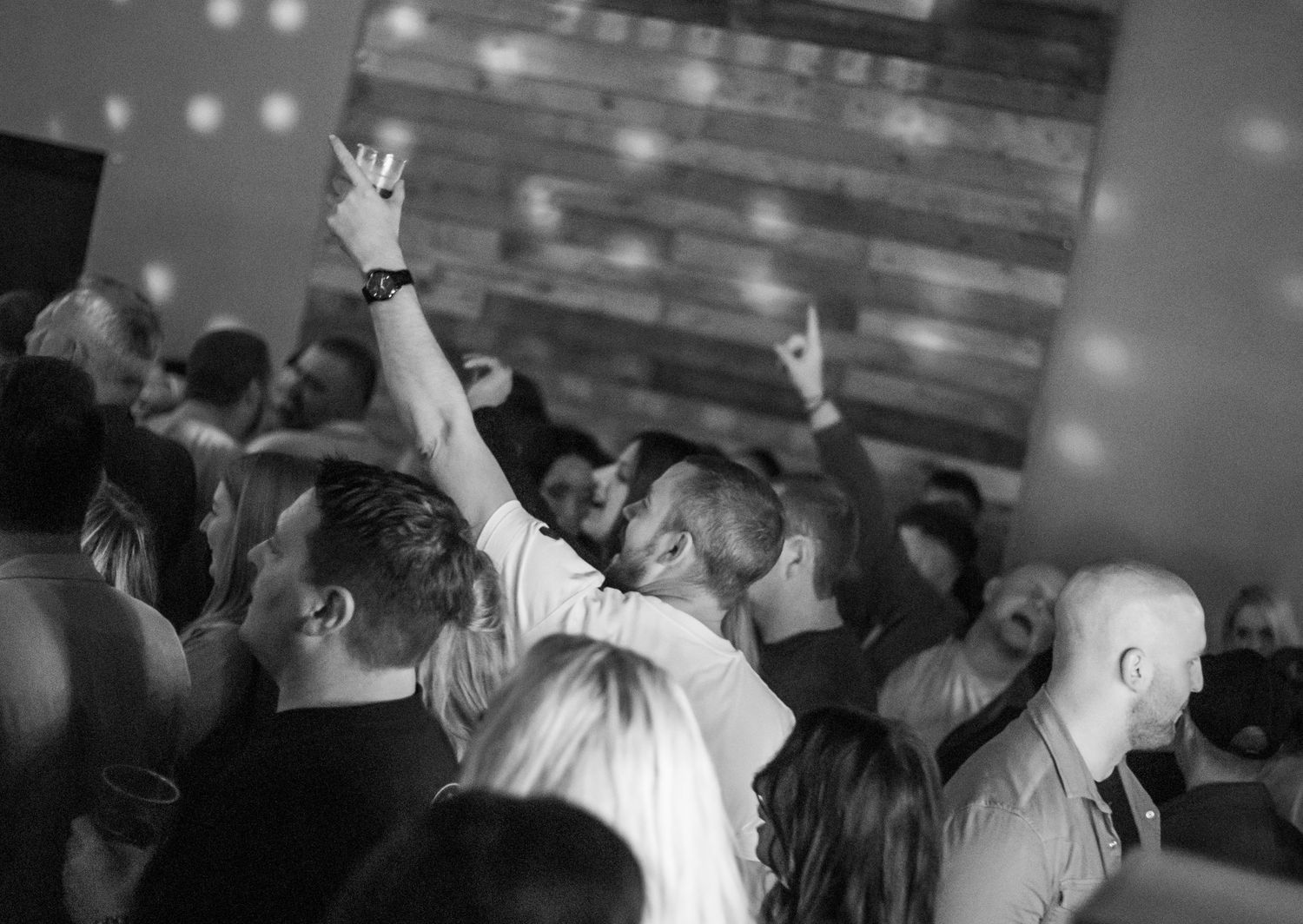 Black and white image of concert crowd with raised hands during performance.