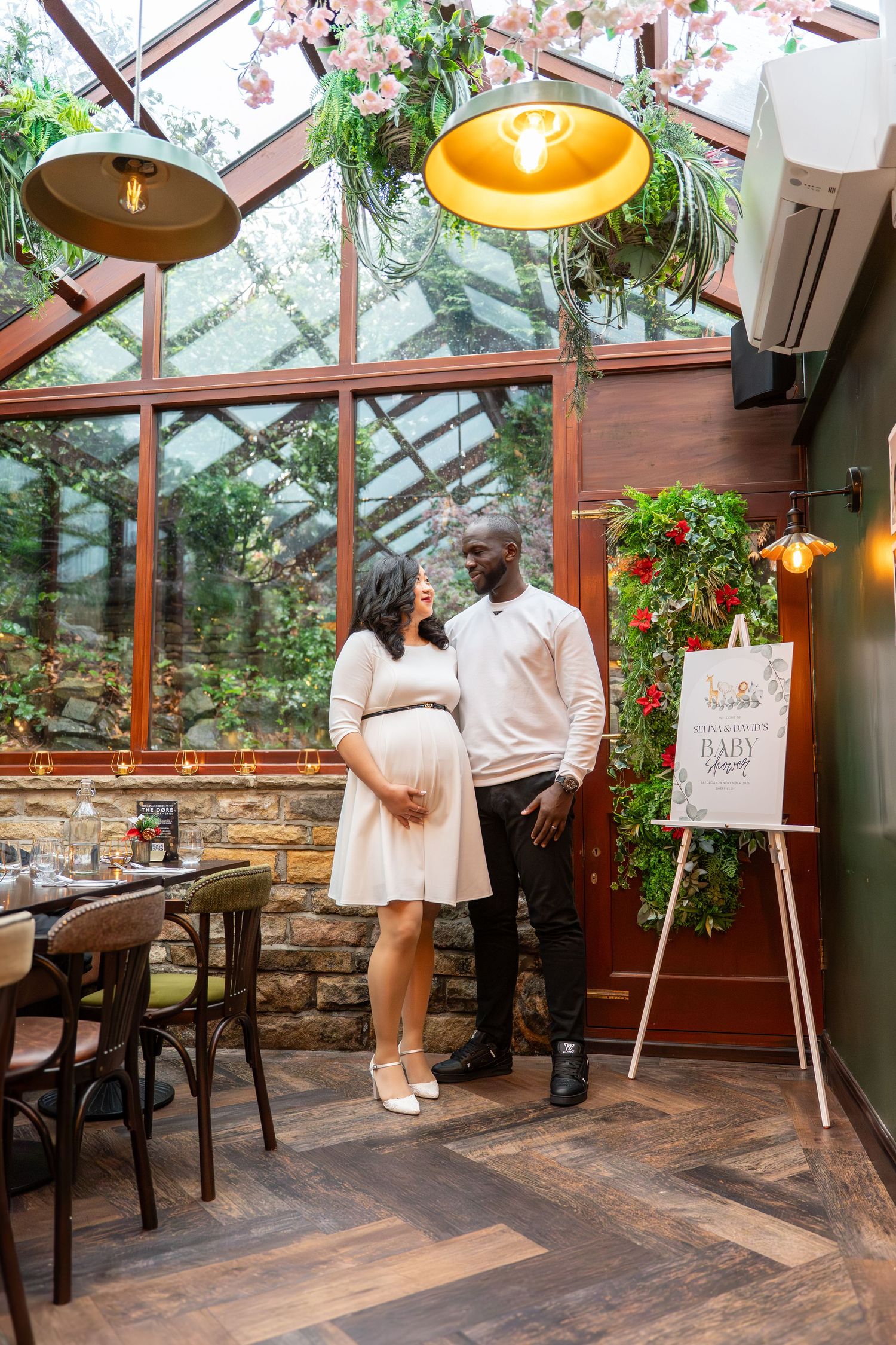 Elegant baby shower setup in a conservatory with pendant lights and stone accent wall.