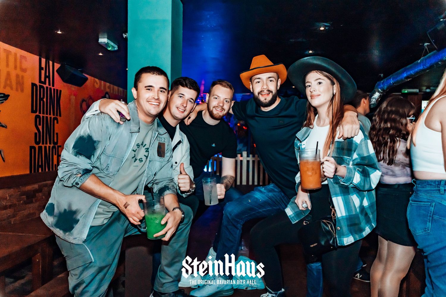 Friends posing and celebrating together at Steinhaus bar during a night out.