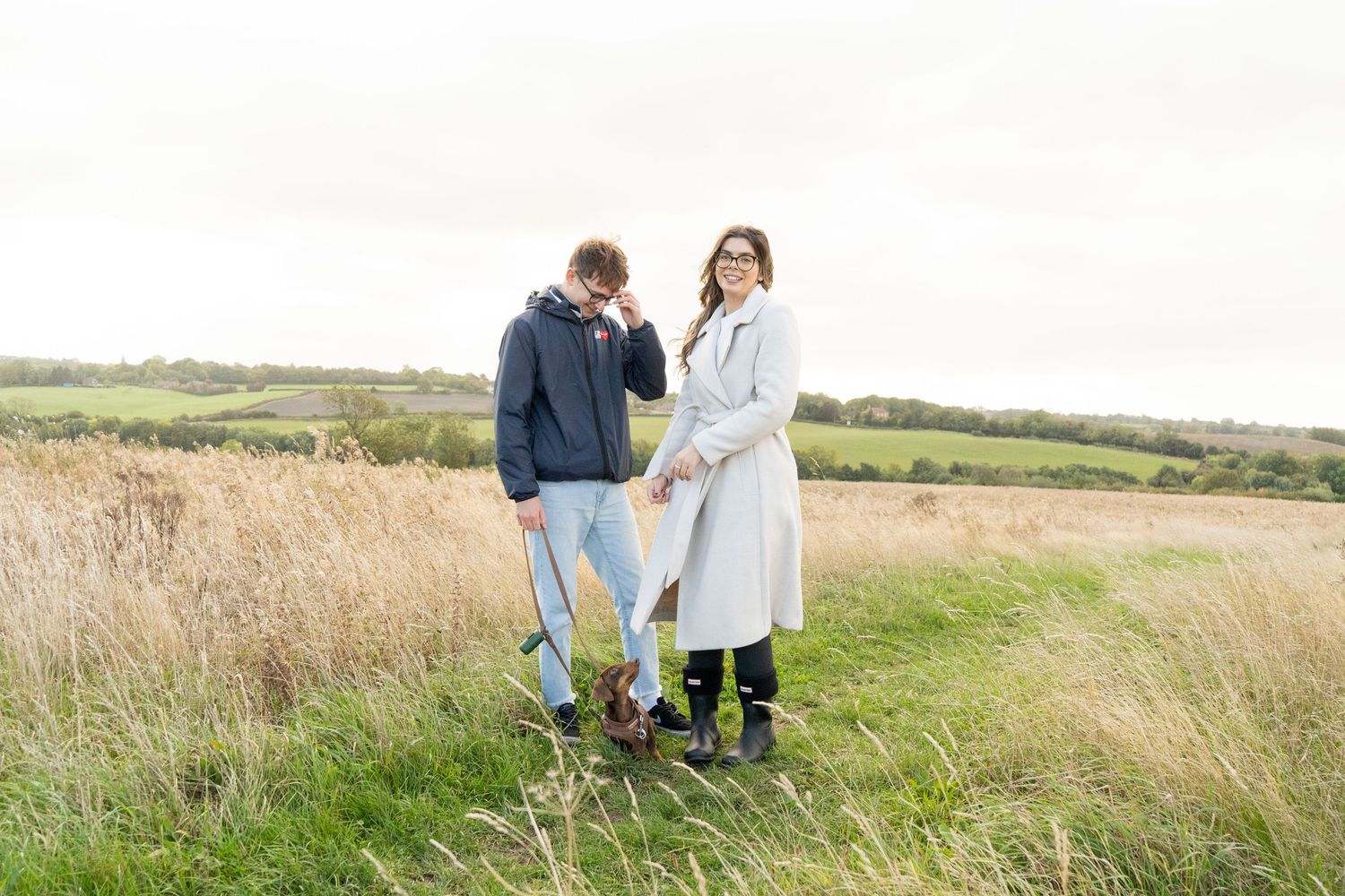 A couple enjoying a playful moment together in a grassy meadow.