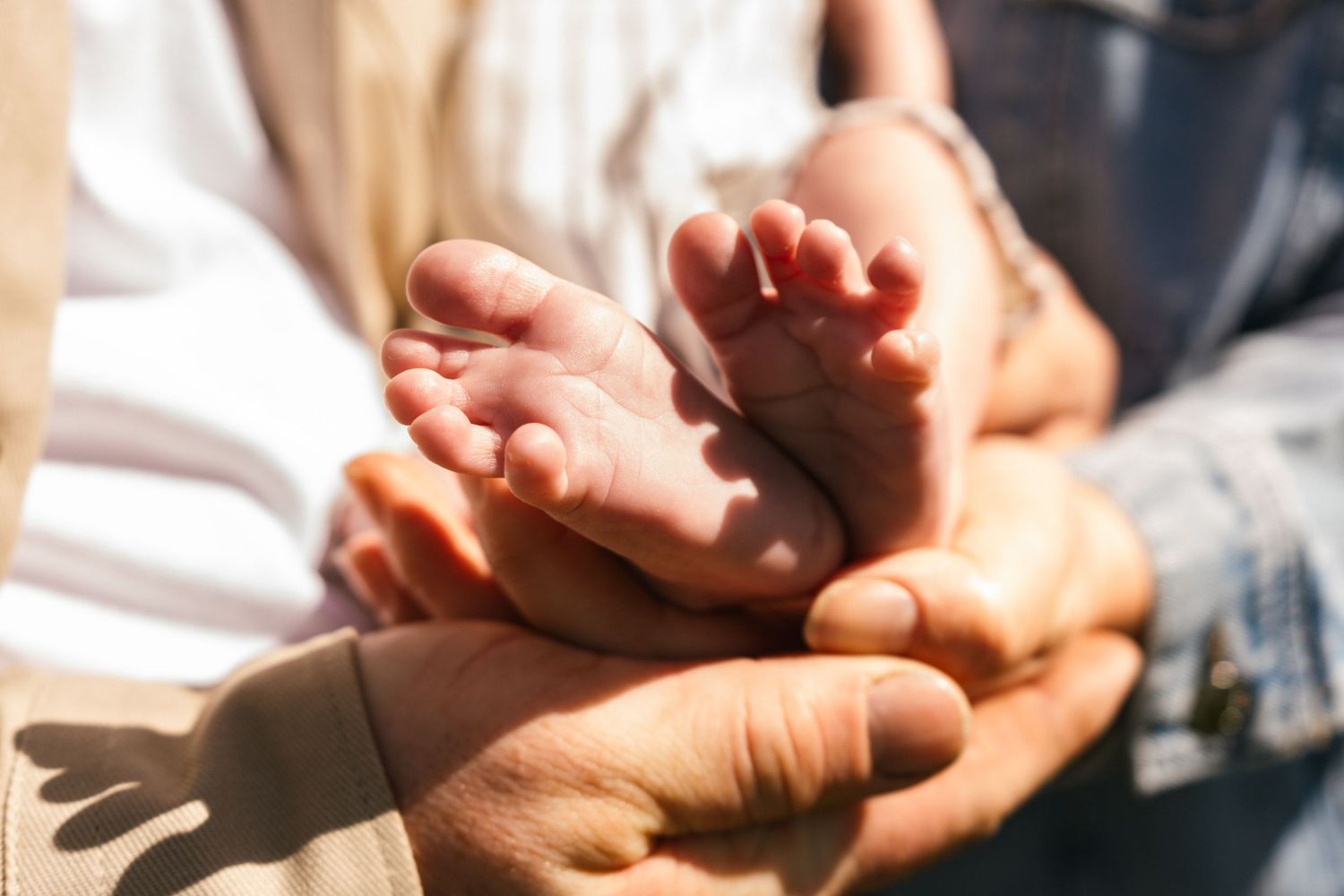 Close-up of tiny baby feet being gently held in adult hands.