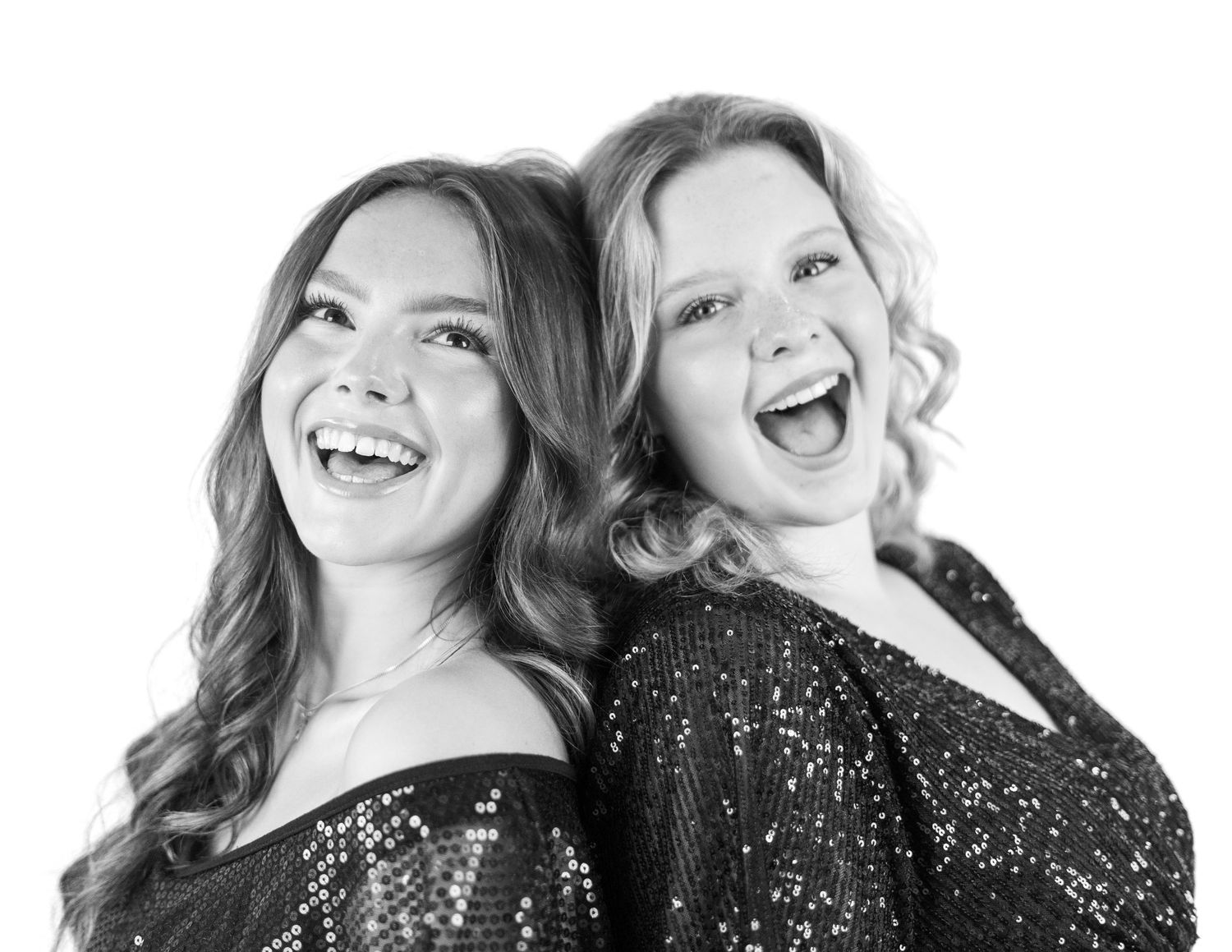 Black and white portrait of two performers laughing together in sequined costumes.