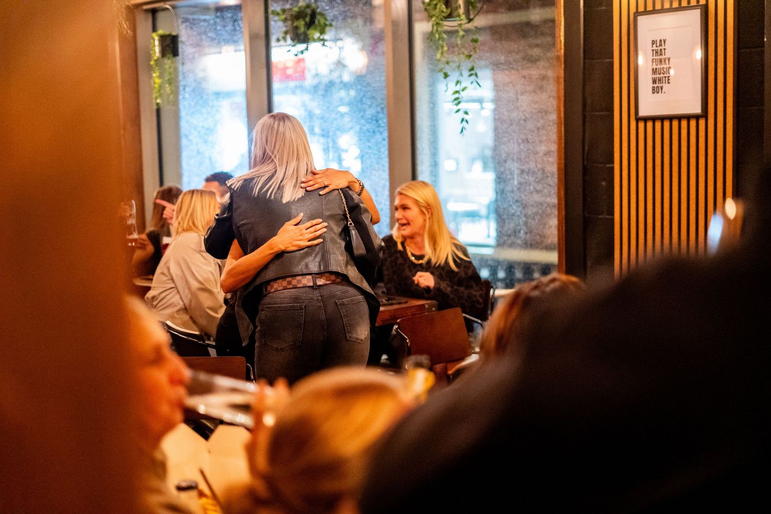 Group gathering in cozy corner of pub with natural light streaming through windows.