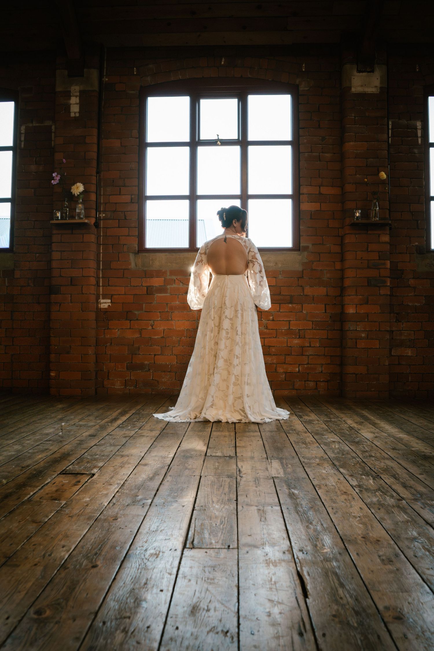 Wedding dress photographed in rustic wooden room with natural lighting.