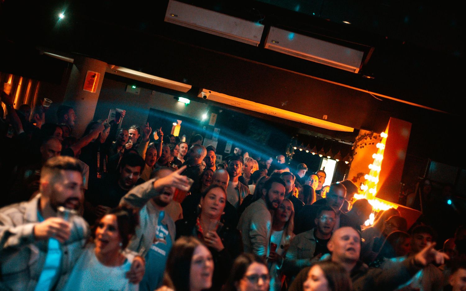 Concert venue with blue lighting and a crowd enjoying a live music performance.