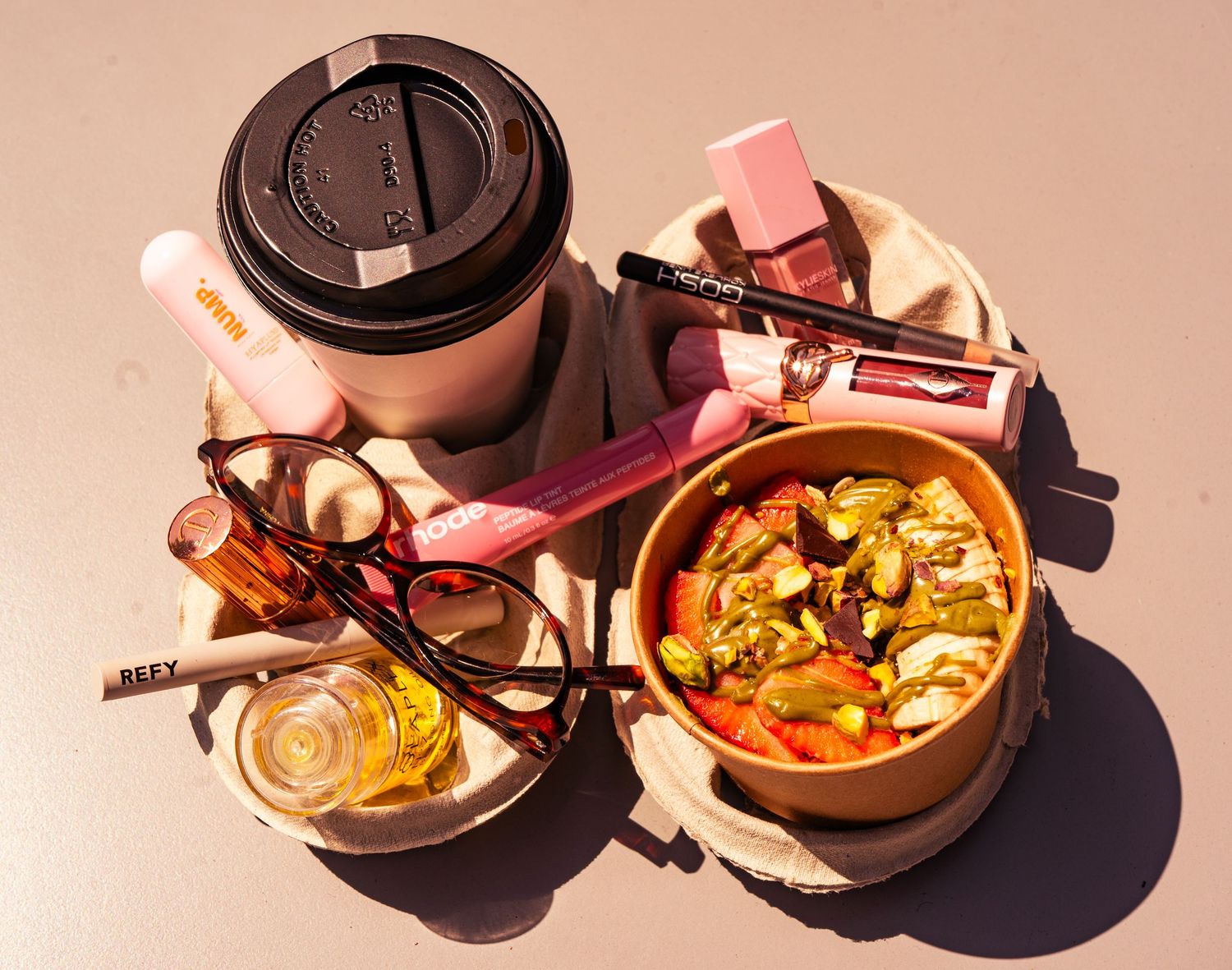 Overhead view of colorful food and drinks arranged on pink surface with natural lighting.