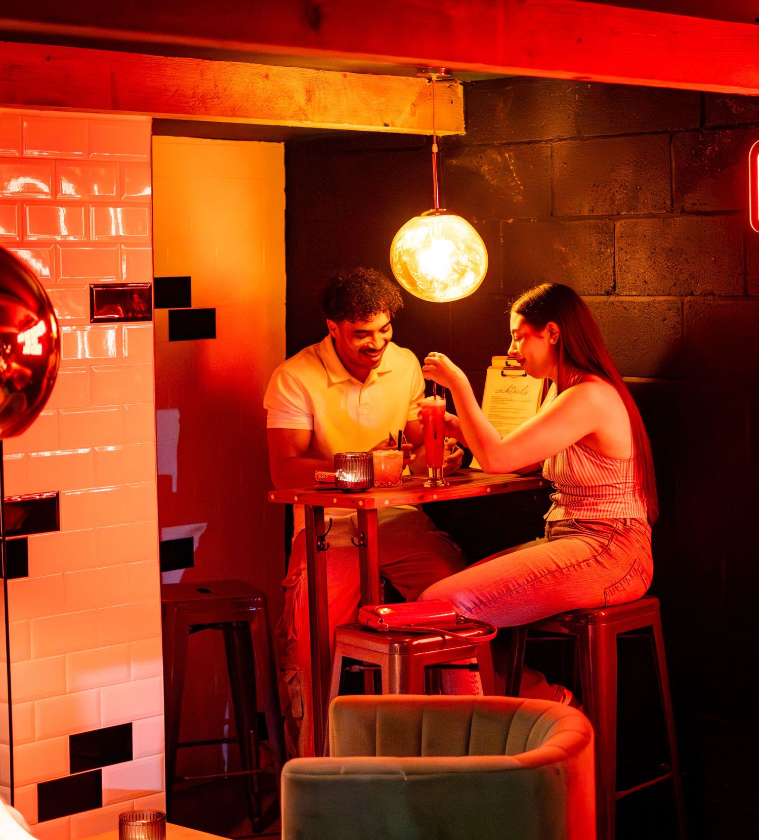 Bar interior with red ambient lighting and cozy seating arrangements.