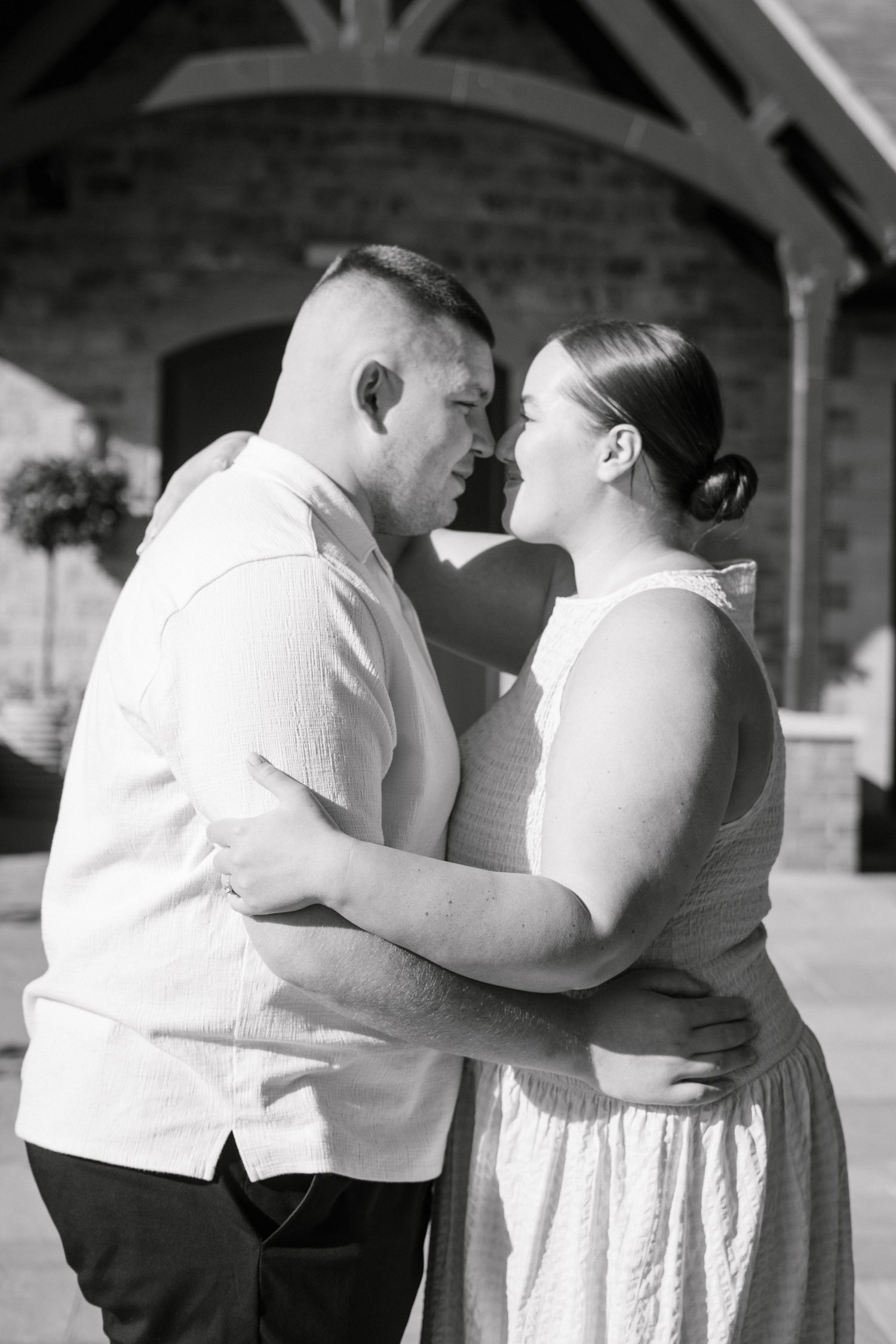 Couple embraces under covered outdoor structure in intimate photoshoot.