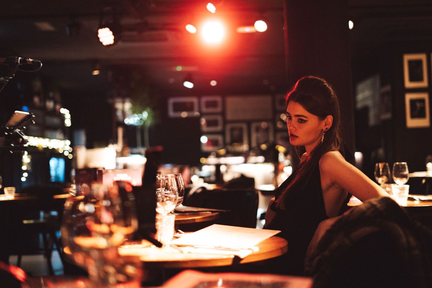 A dimly lit bar scene with red lighting and someone working behind the counter.