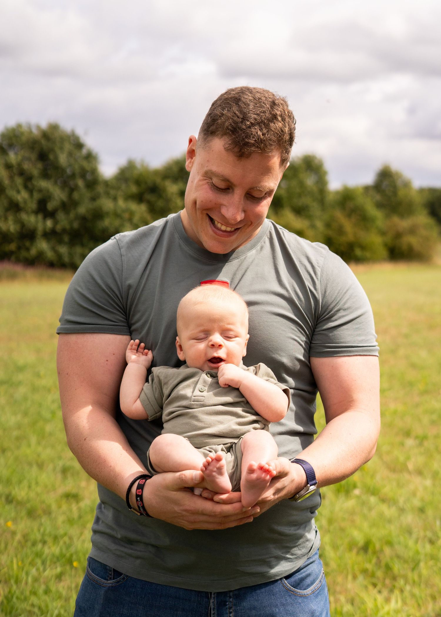 Sweet interactions with a baby in a gray onesie on a grassy field.