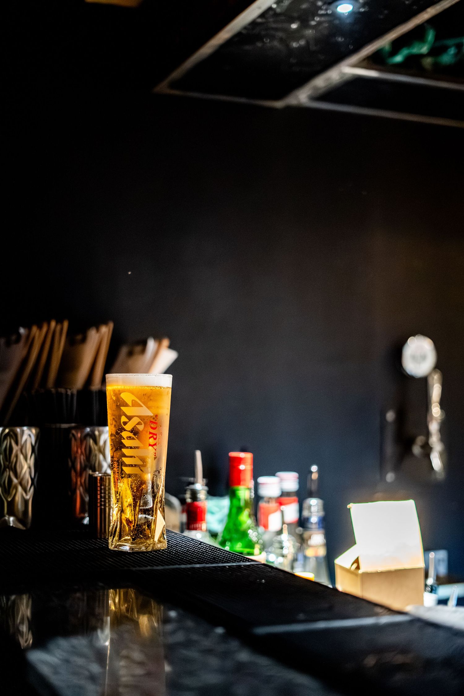 Dimly lit bar counter with amber-colored drinks in crystal glasses.