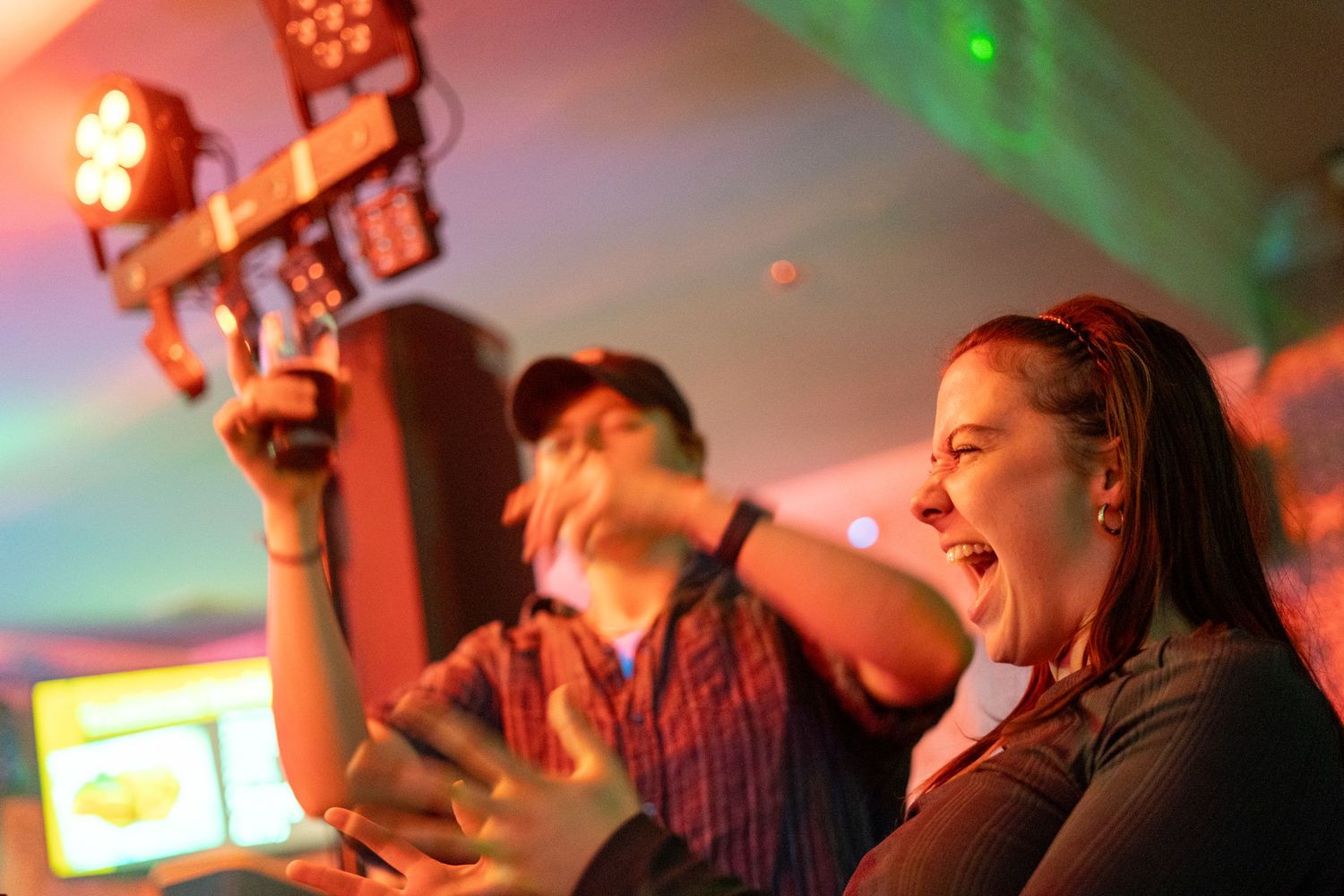People enjoying a lively moment at a music venue with colorful red and green lighting effects.