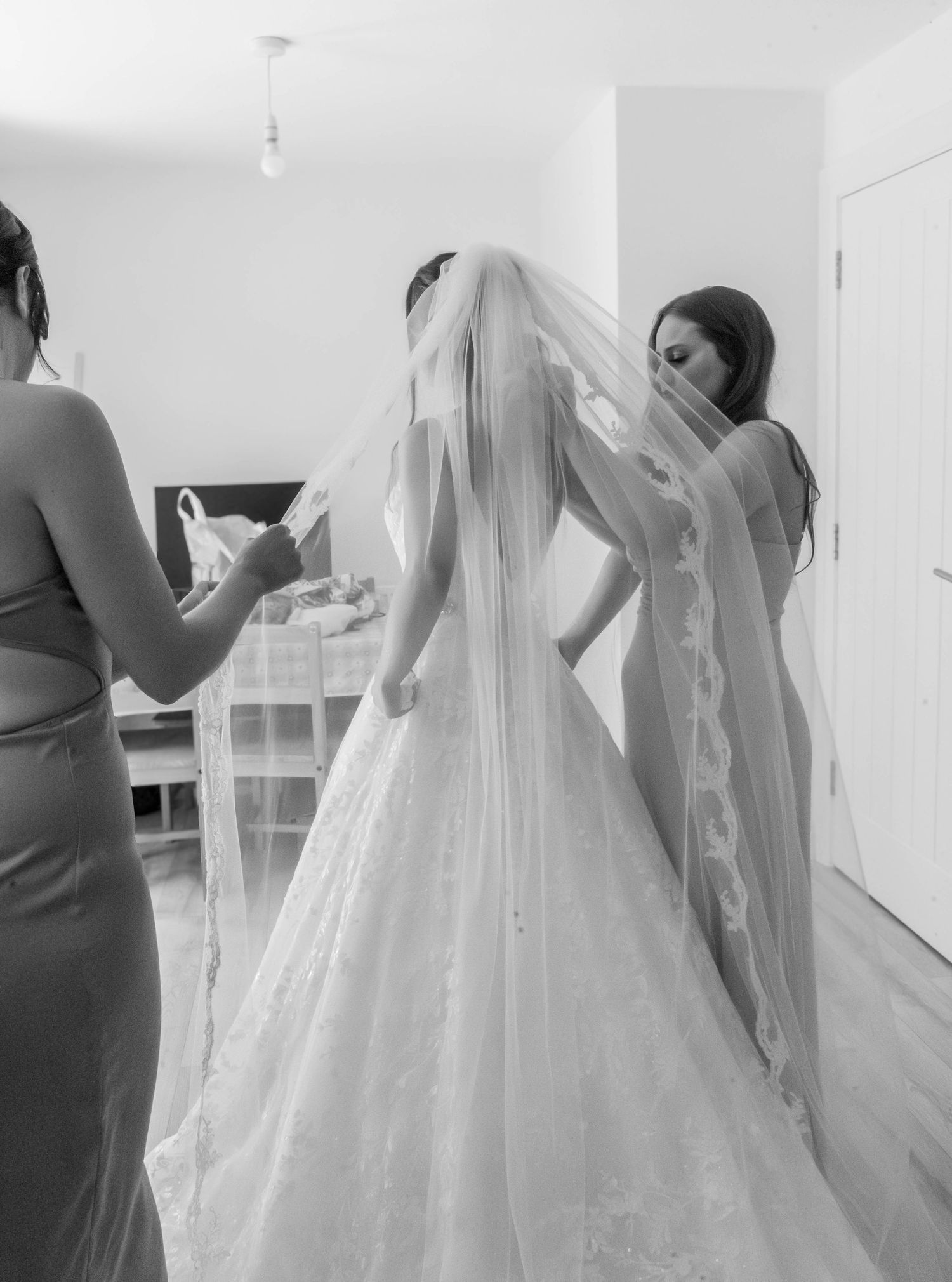 Behind-the-scenes wedding dress preparation in a bright white room.