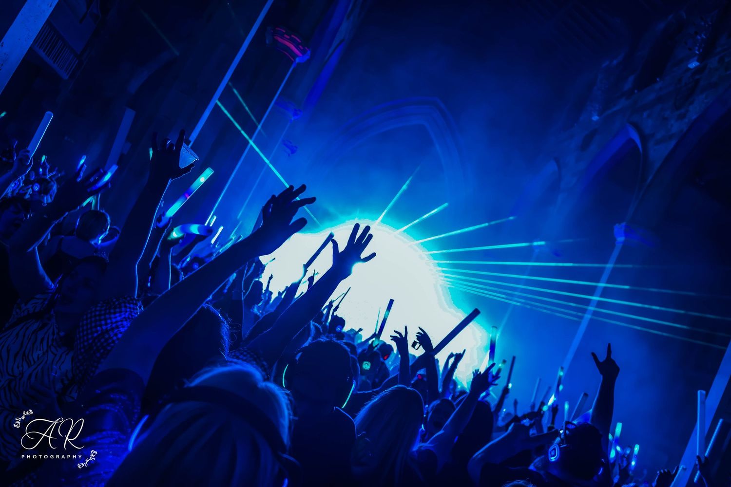 Concert crowd silhouettes against dramatic blue stage lighting during a live performance.